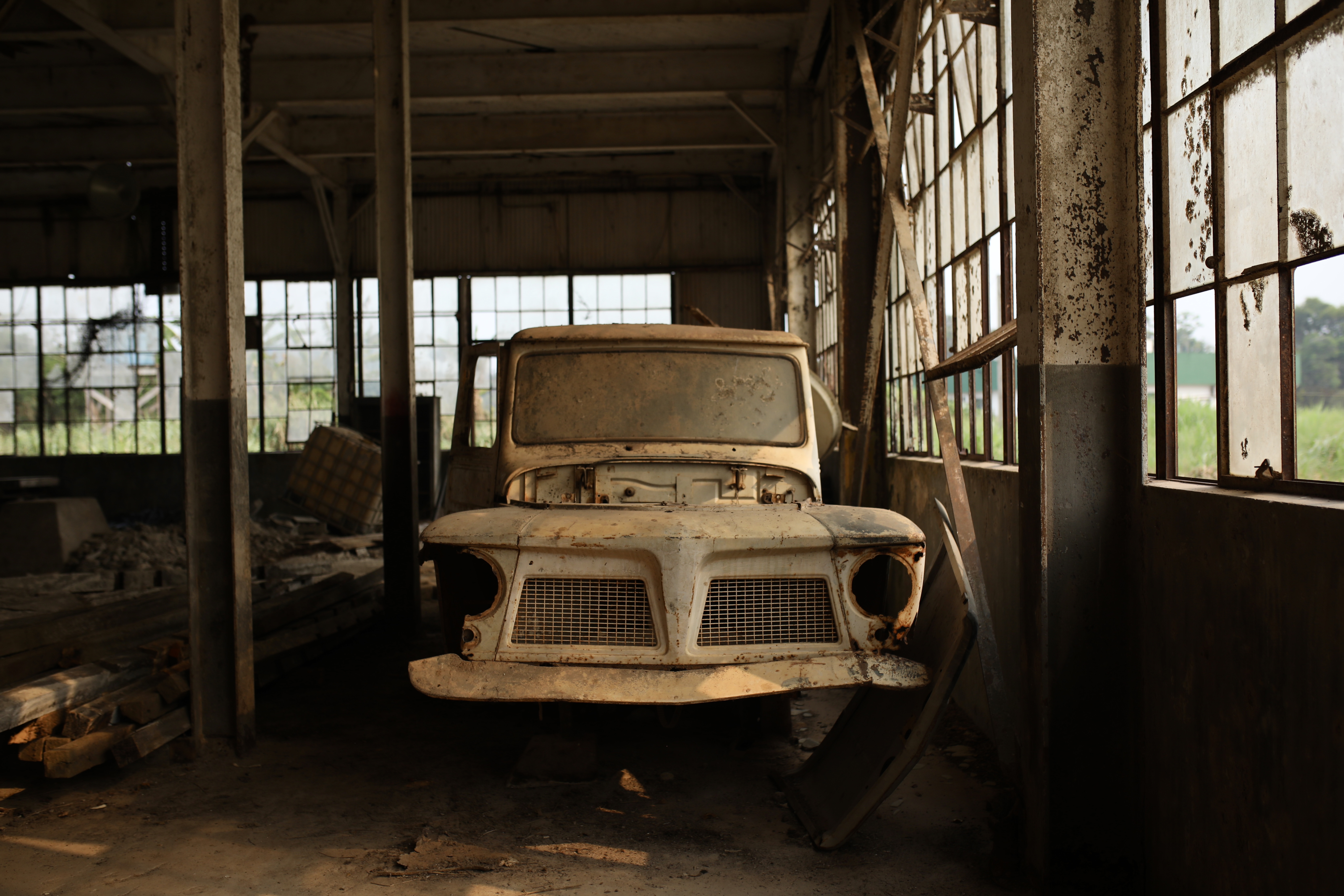 A rusted, antique truck sits in an abandoned warehouse.