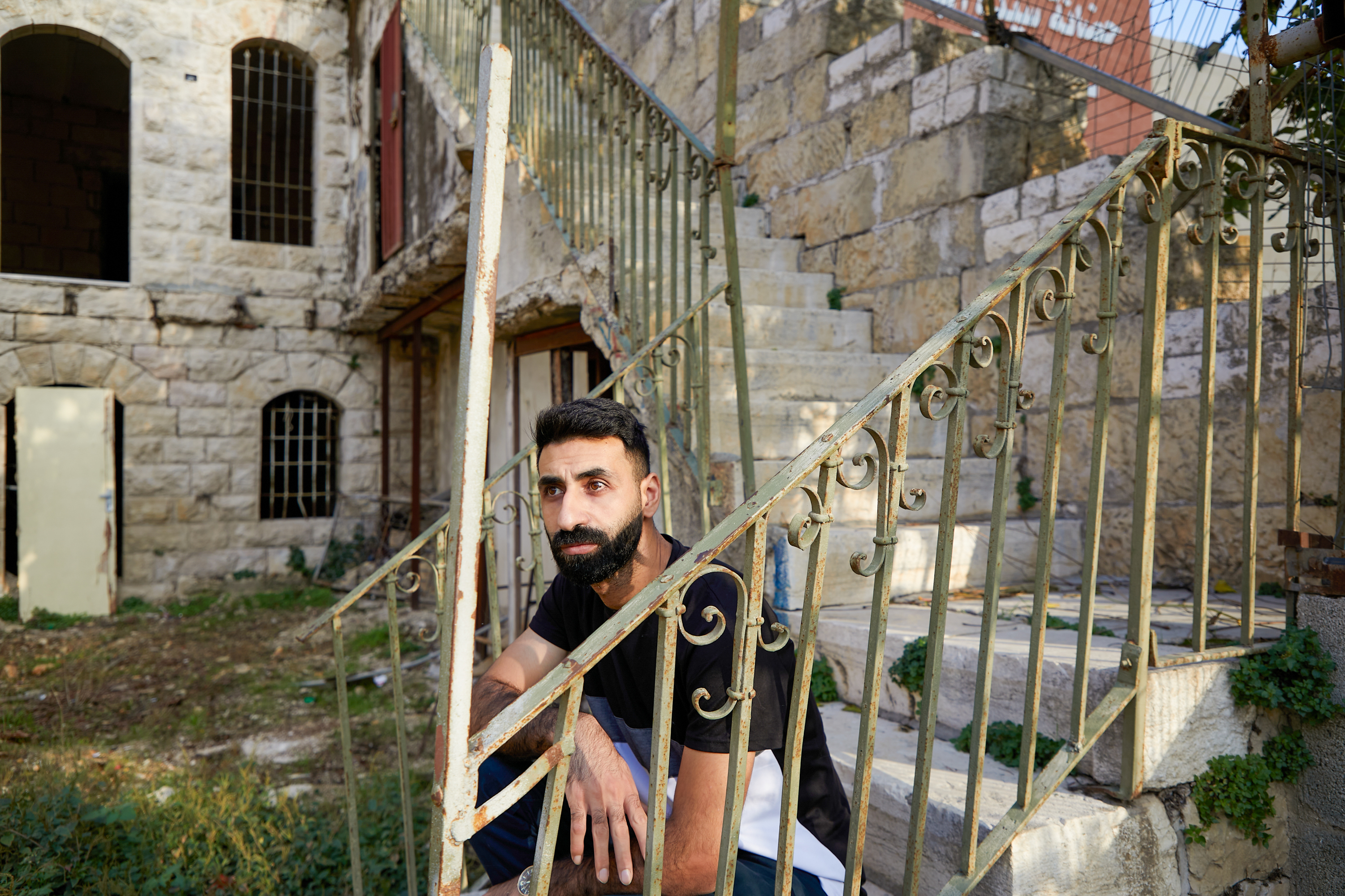 Osama crouches on some outdoor steps