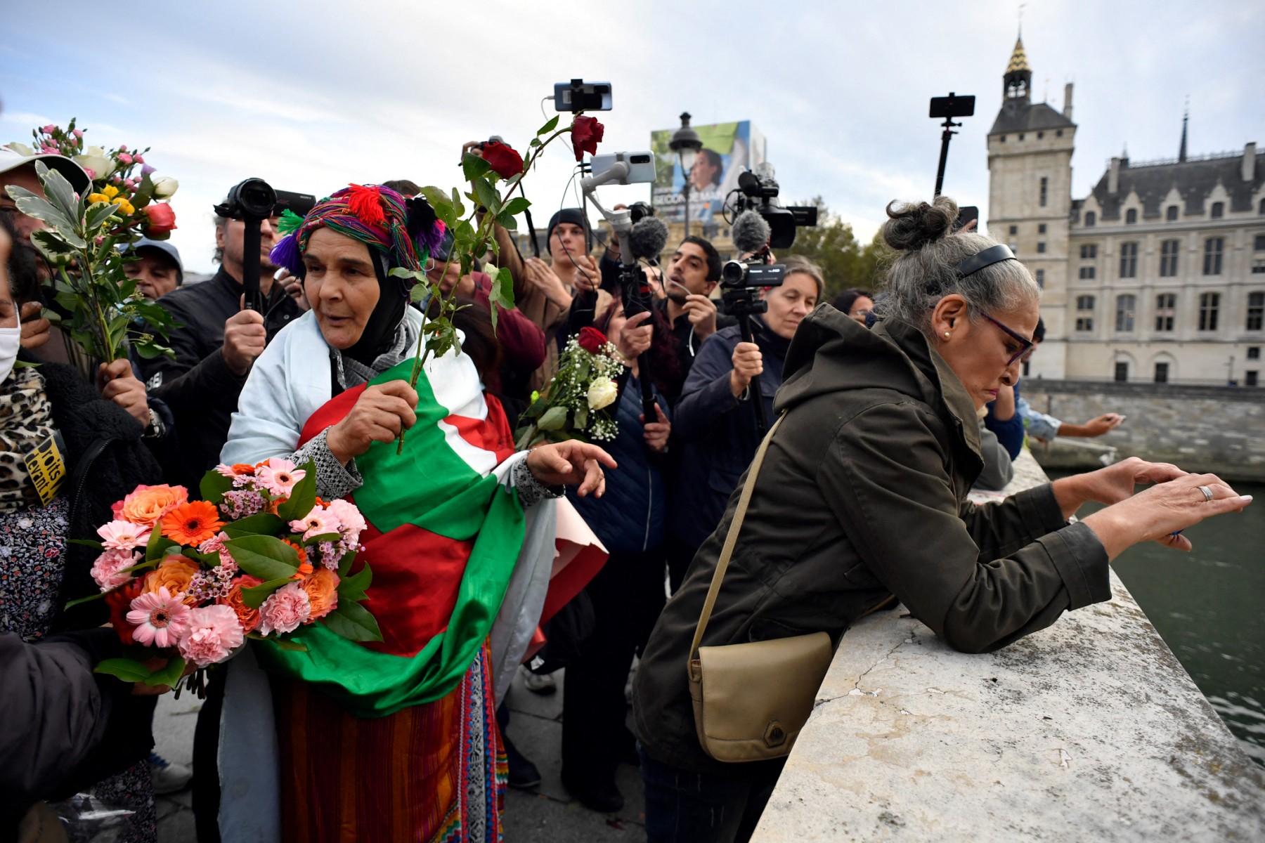 Women throw roses into the Seine river