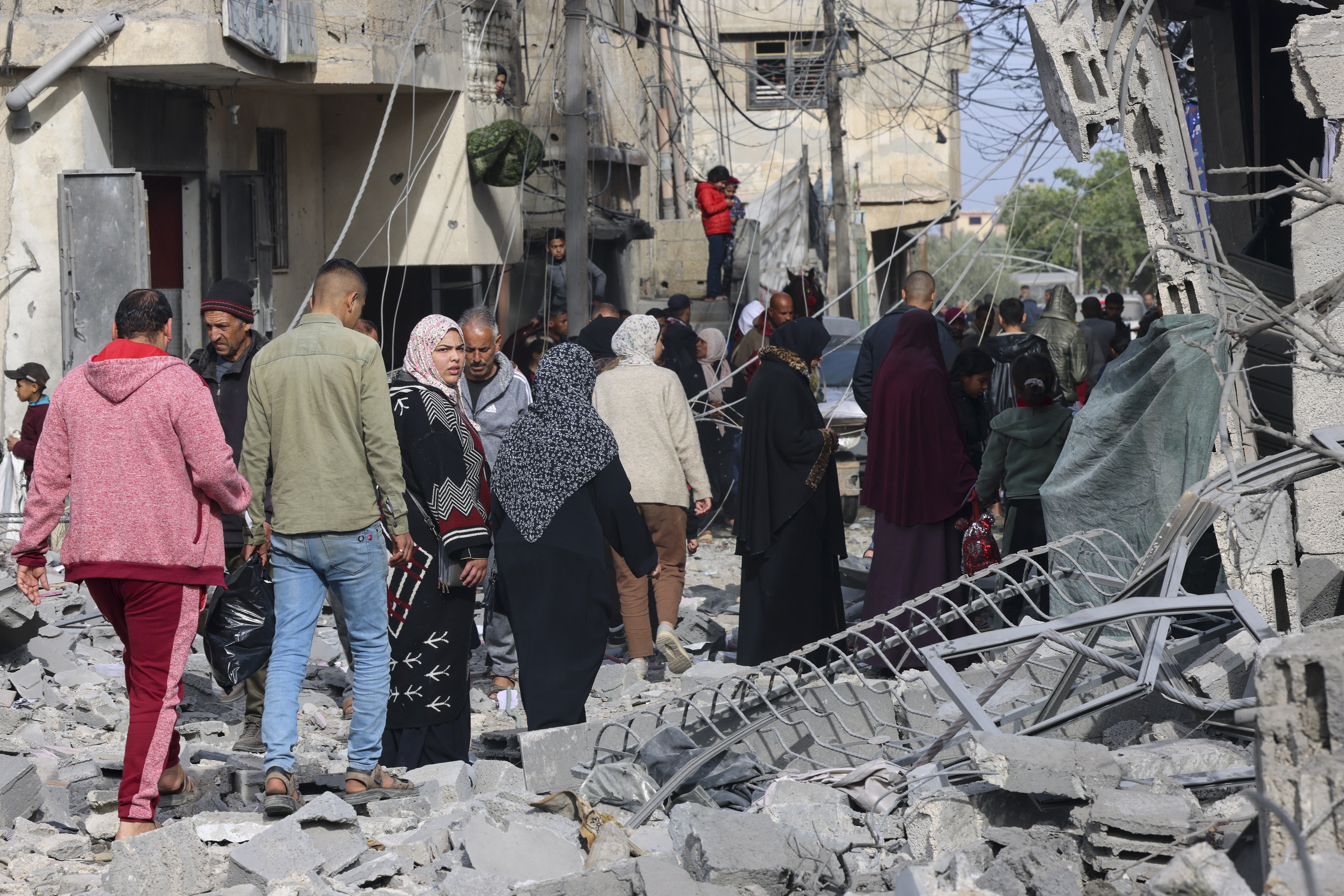 People inspect the damage in the rubble of buildings damaged during Israeli bombardment in Rafah, on the southern Gaza Strip on February 12, 2024, amid ongoing battles between Israel and the militant group Hamas. - Israel announced on February 12 the rescue of two hostages in the southern Gaza city of Rafah, where the Hamas-run health ministry said "around 100" Palestinians including children were killed in heavy overnight air strikes. (Photo by SAID KHATIB / AFP)