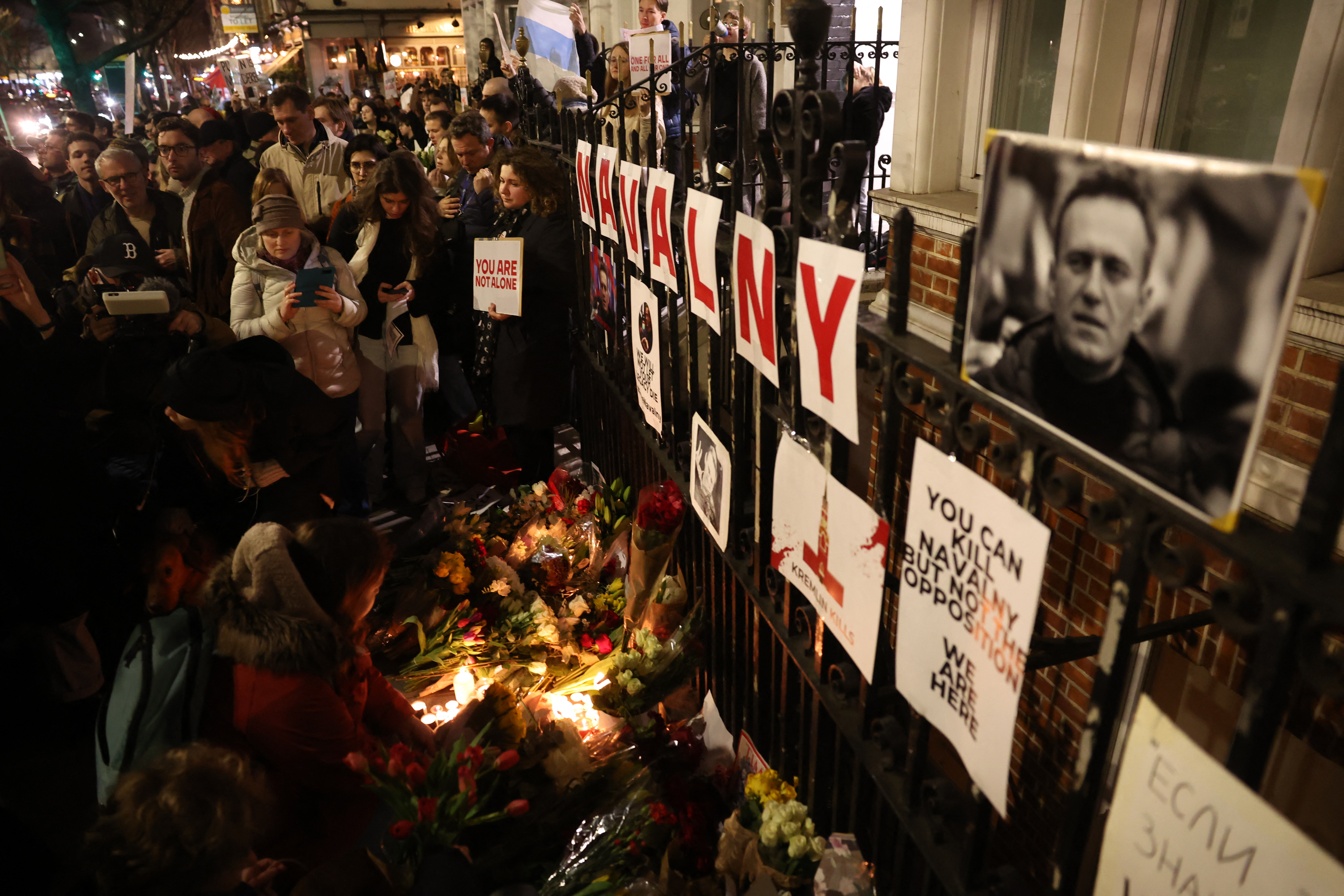People leave candles and flowers outside the Russian Embassy in London on February 16