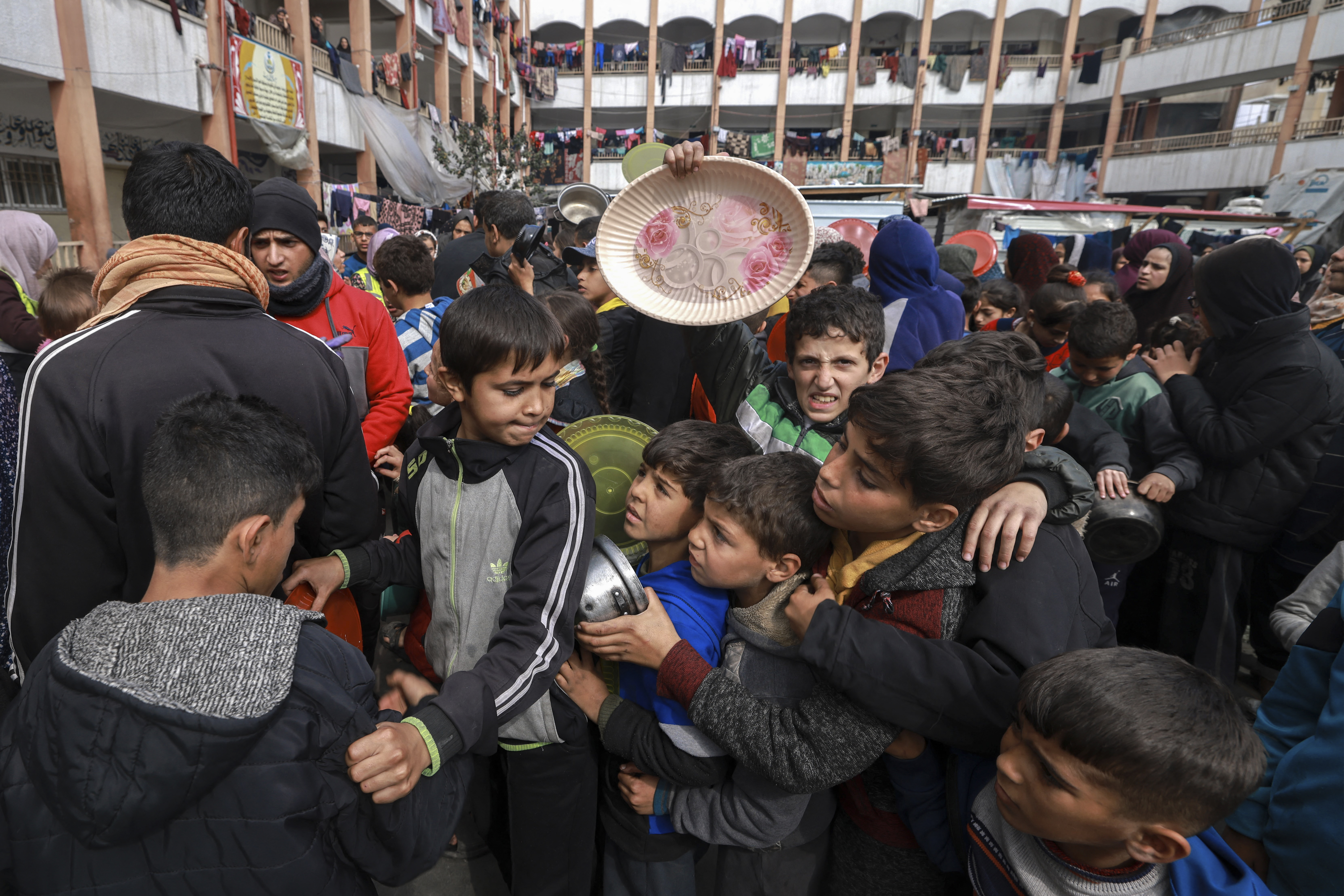 Displaced Palestinian children gather to receive food at a school in Rafah in southern Gaza
