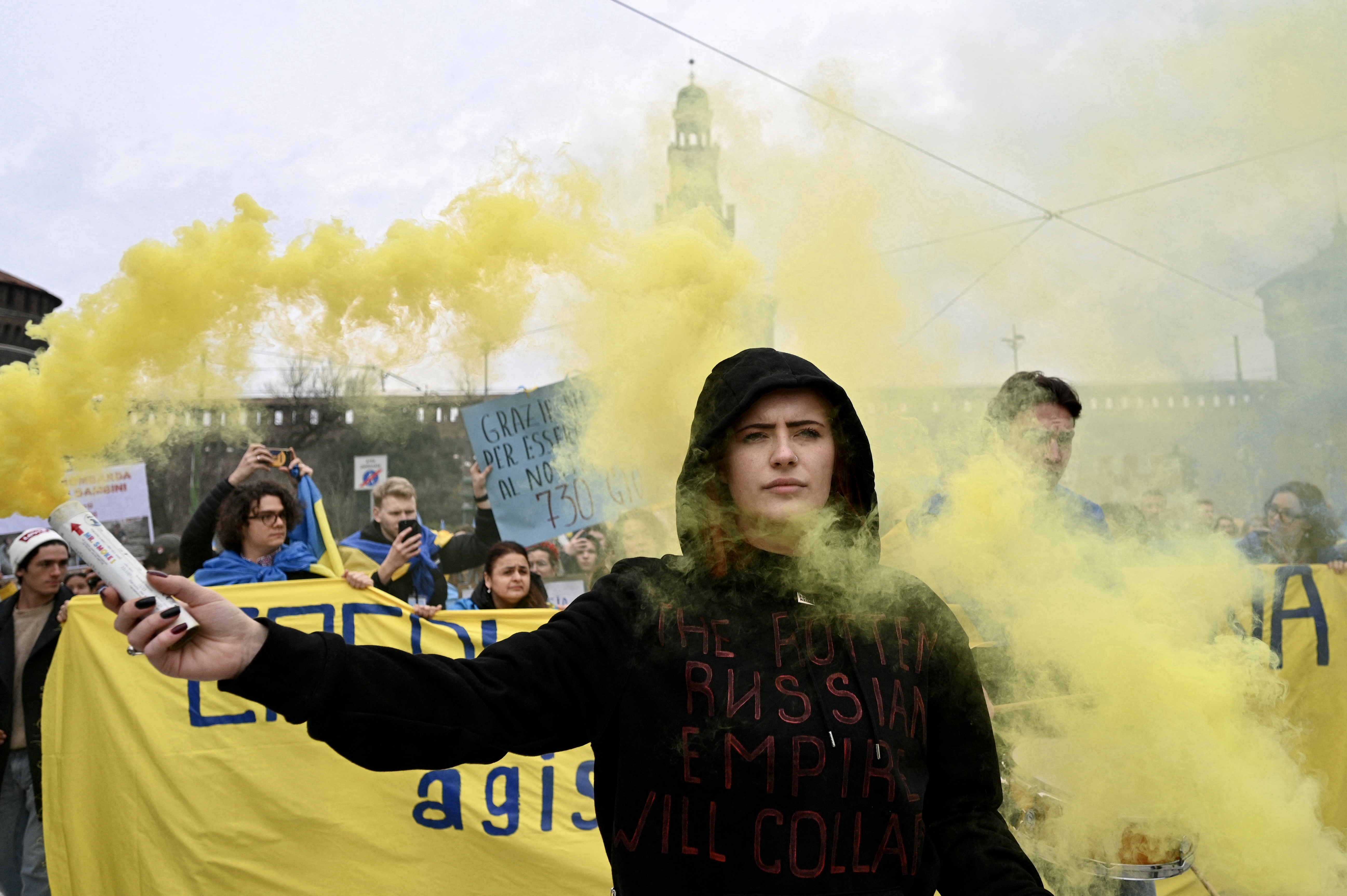 Protesters hold blue and yellow smoke grenades during a demonstration to protest against the invasion of Ukraine by Russia, on February 24