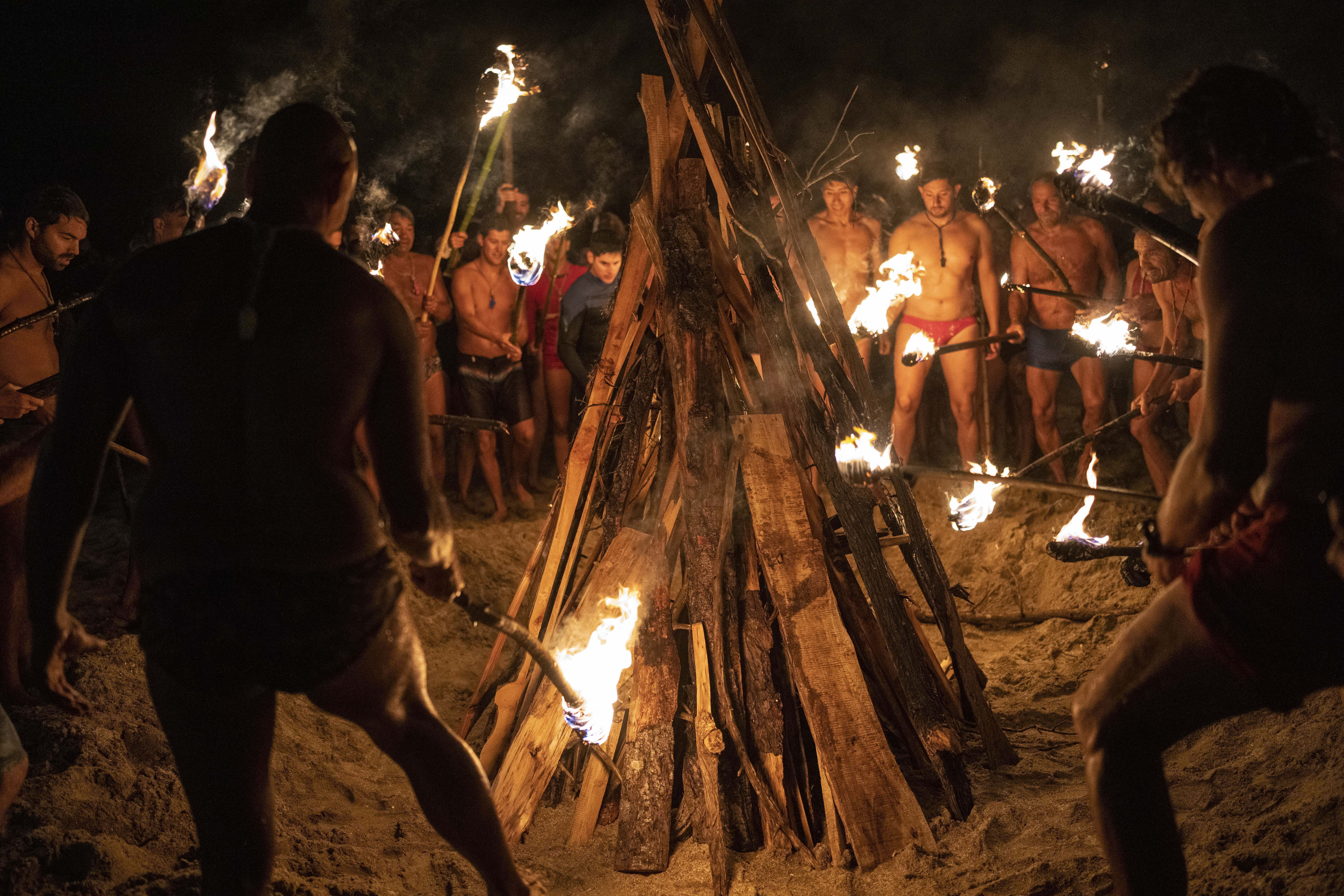 Lifeguards start a bonfire with torches to commemorate Lifeguard Day, to honor their commitment to safety and aquatic rescue, in Mar Azul, Argentina, Wednesday, Feb. 14