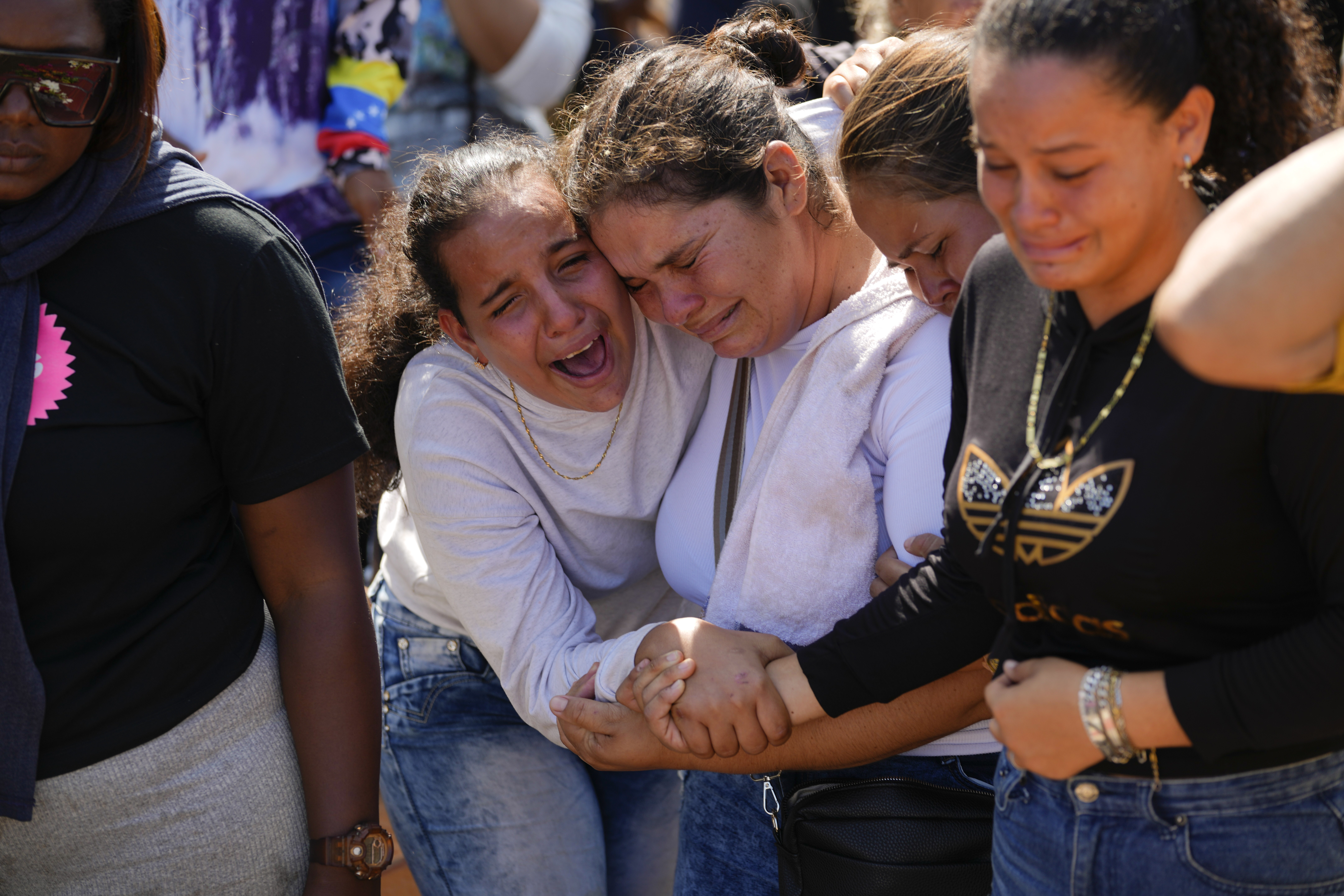 A sister of miner Santiago Mora, left, cries with other relatives as he is buried at the cemetery in La Paragua, Bolivar state, Venezuela, Thursday, Feb. 22