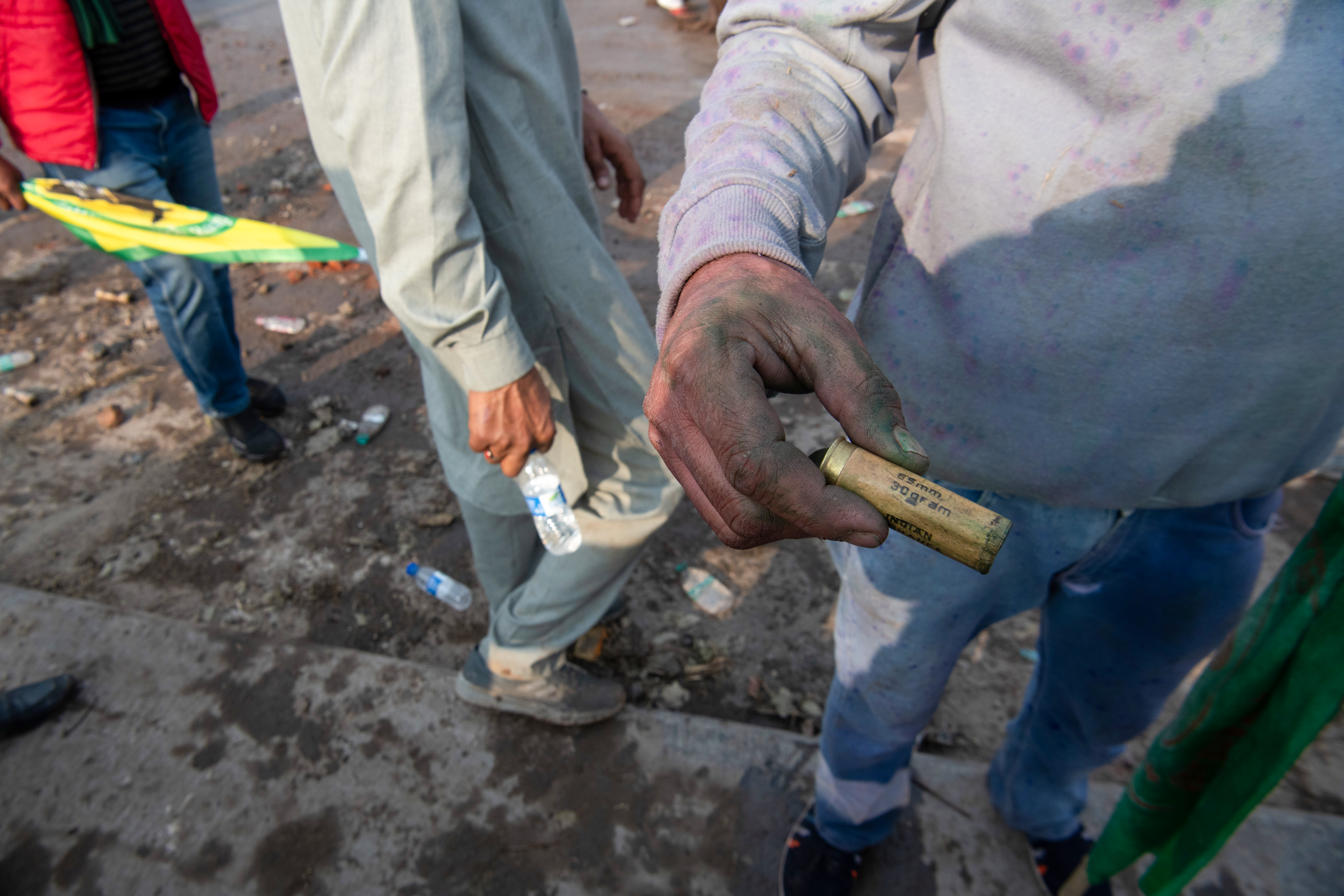 A protesting farmer displays a rubber bullet casing used to disperse protestors at the Sindhu border, aiming to prevent them from advancing towards Delhi.
