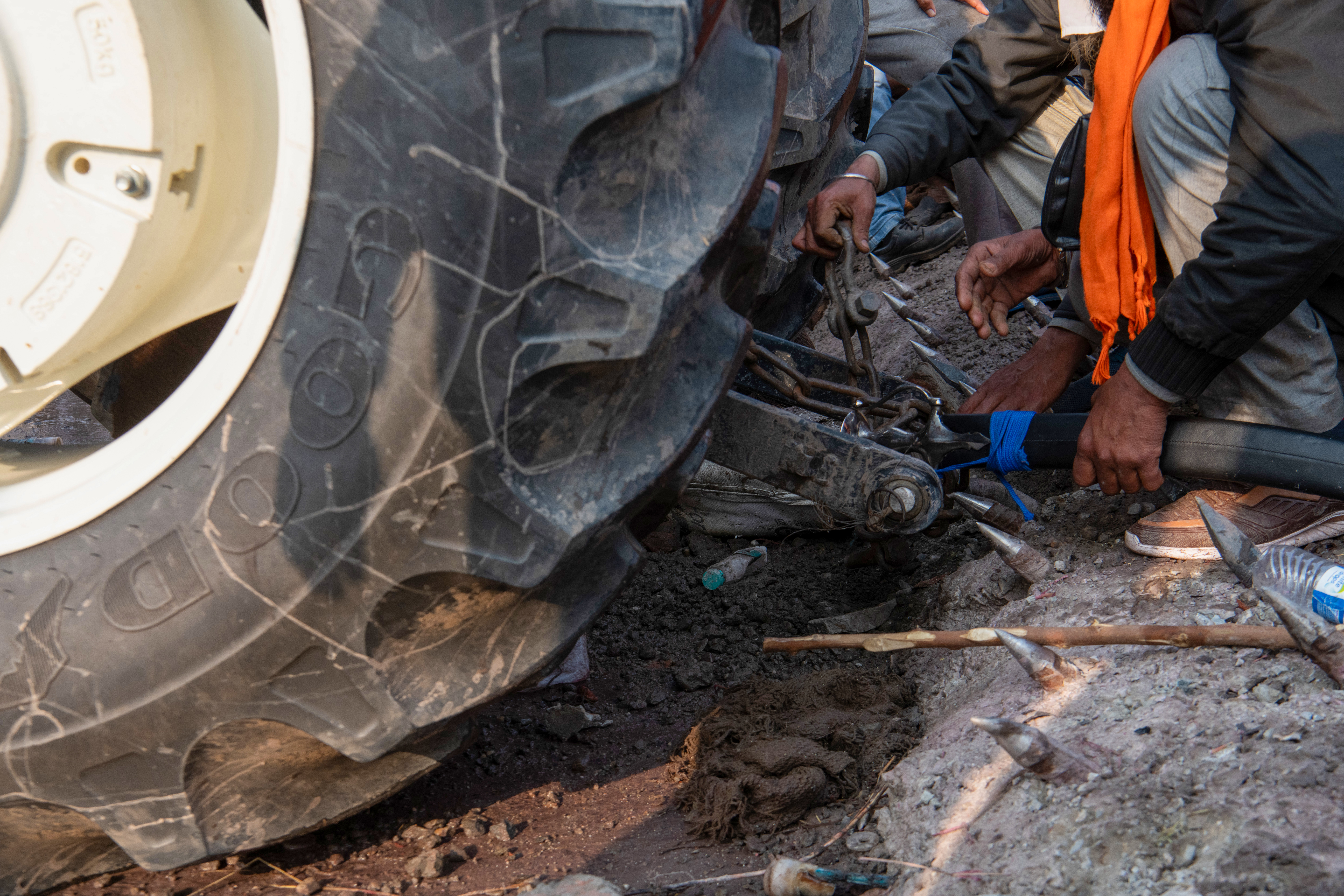 Farmers maneuver a tractor through a field of iron nails, strategically placed to thwart farmers from accessing Delhi at the Sandhu border. Despite authorities fortifying the area with multiple barricades and nails, these gamers persist in their mission.