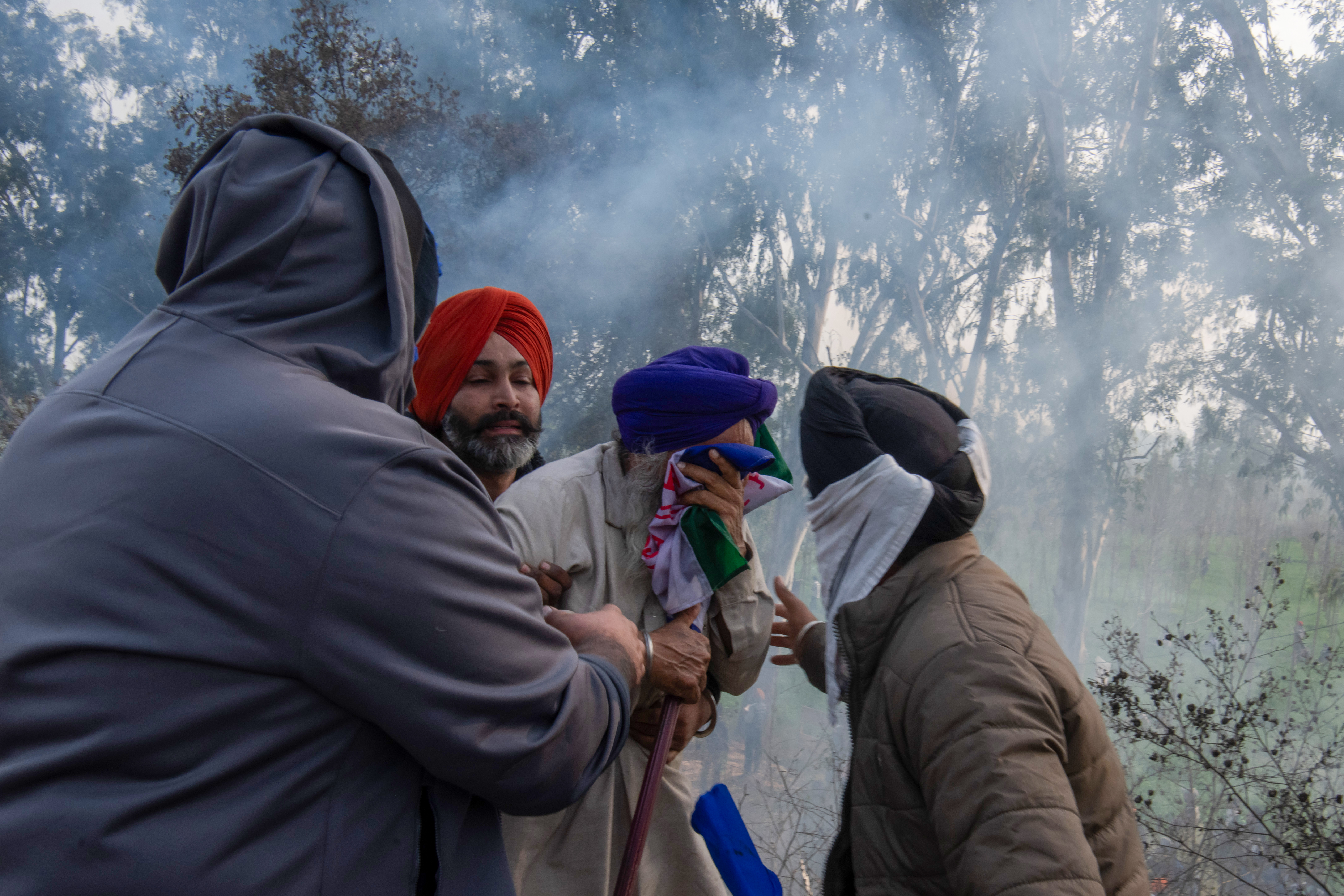 A protesting farmer shields his eyes from tear gas as police attempt to deter farmers from advancing towards Delhi. Authorities employed drone shells to disperse the gathered farmers at the Sandhu border, aiming to thwart their movement into the capital to advocate for their demands.