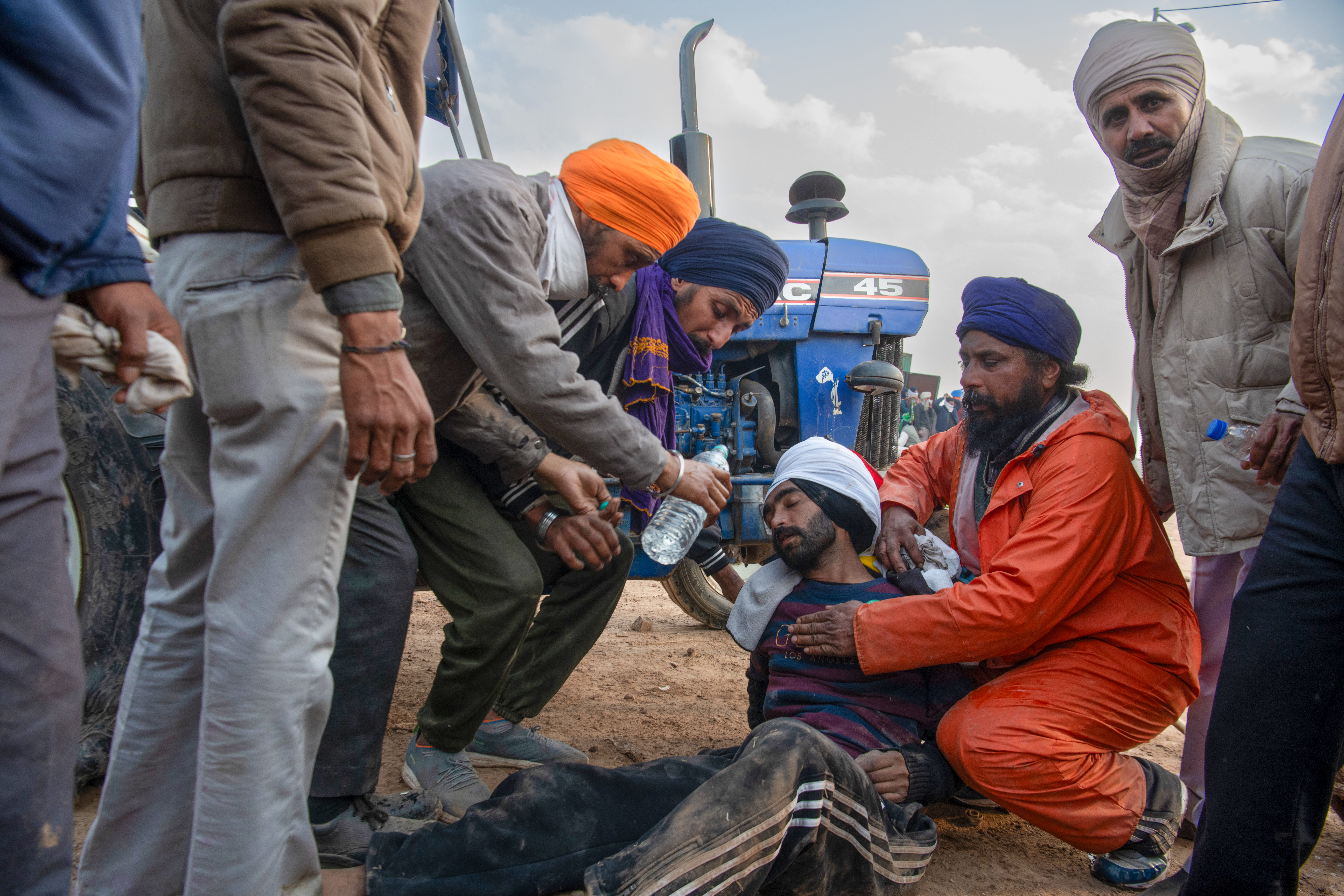 Protesting farmers offer water to a fellow who fainted during the protest at the Shambhu village border between Haryana and Delhi. Authorities stopped the marching farmers and fired tear gas shells, water cannons, and rubber bullets to prevent them from entering Delhi.