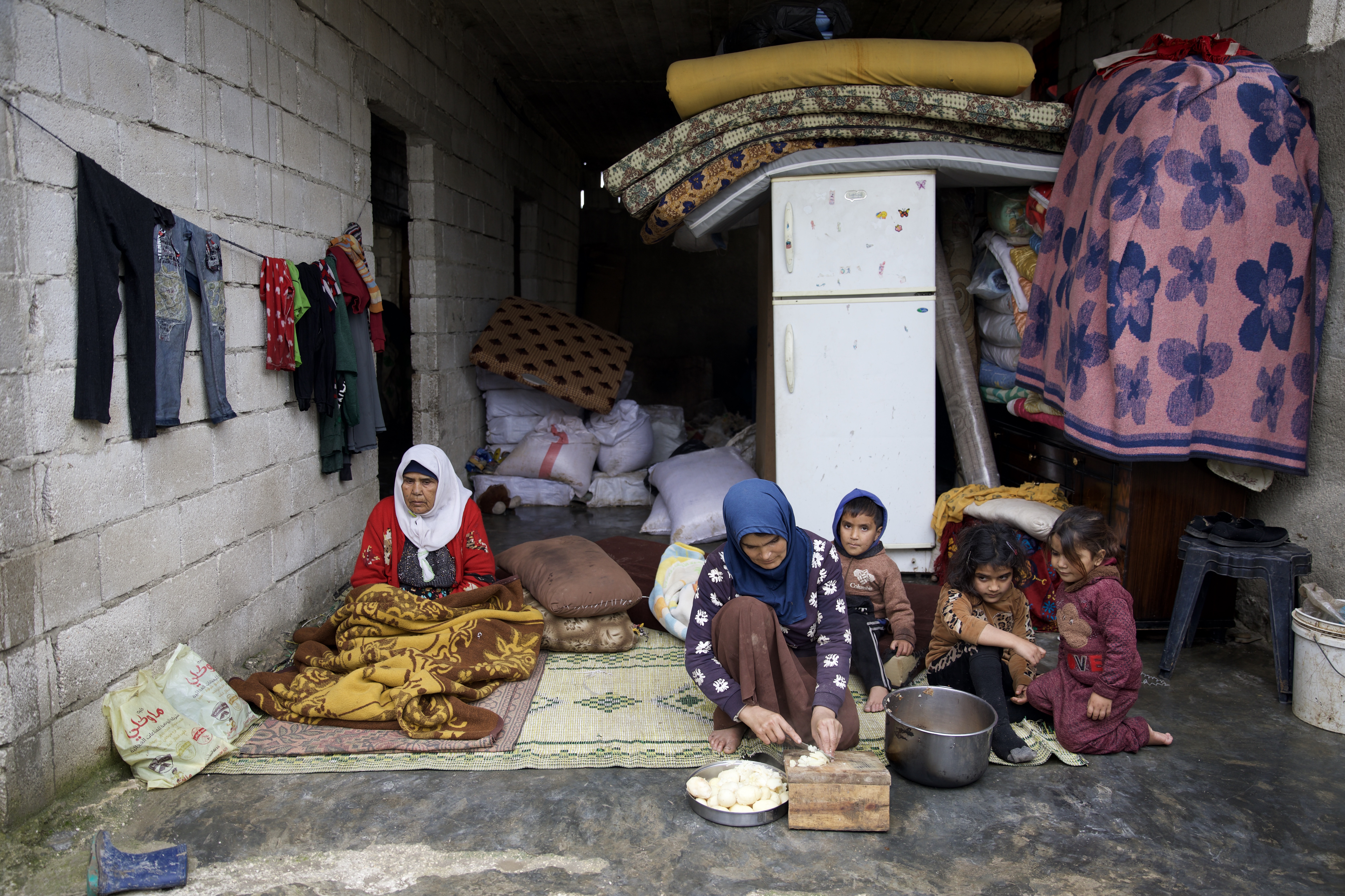 Yasmine prepares food in front of her cracked house, using the few items she was able to extract from under the rubble of the kitchen that collapsed after the earthquake.