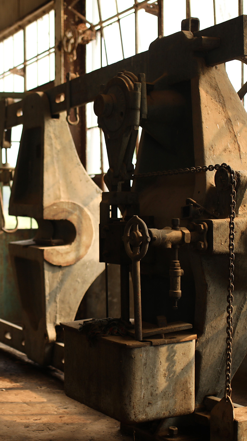 Heavy machinery sits rusted on an old factory floor.
