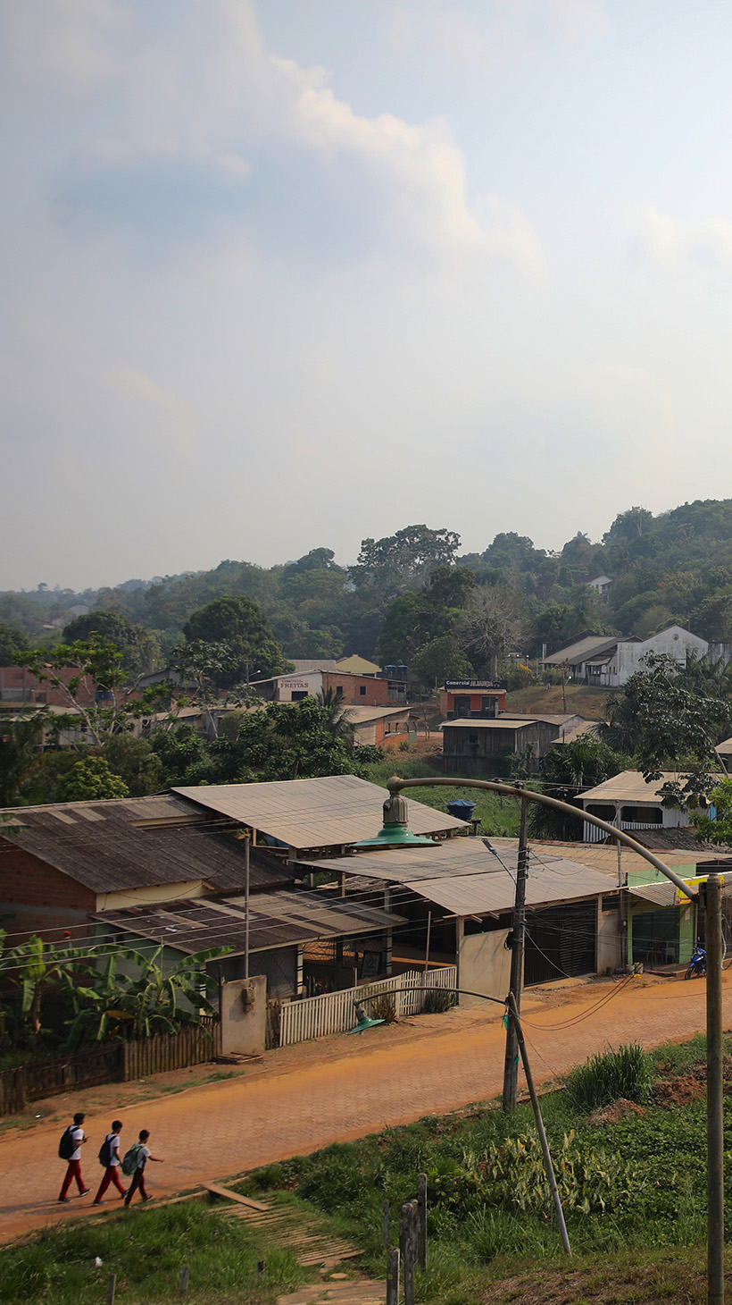A dirt road, lined with modest homes, runs through the Amazon rainforest.