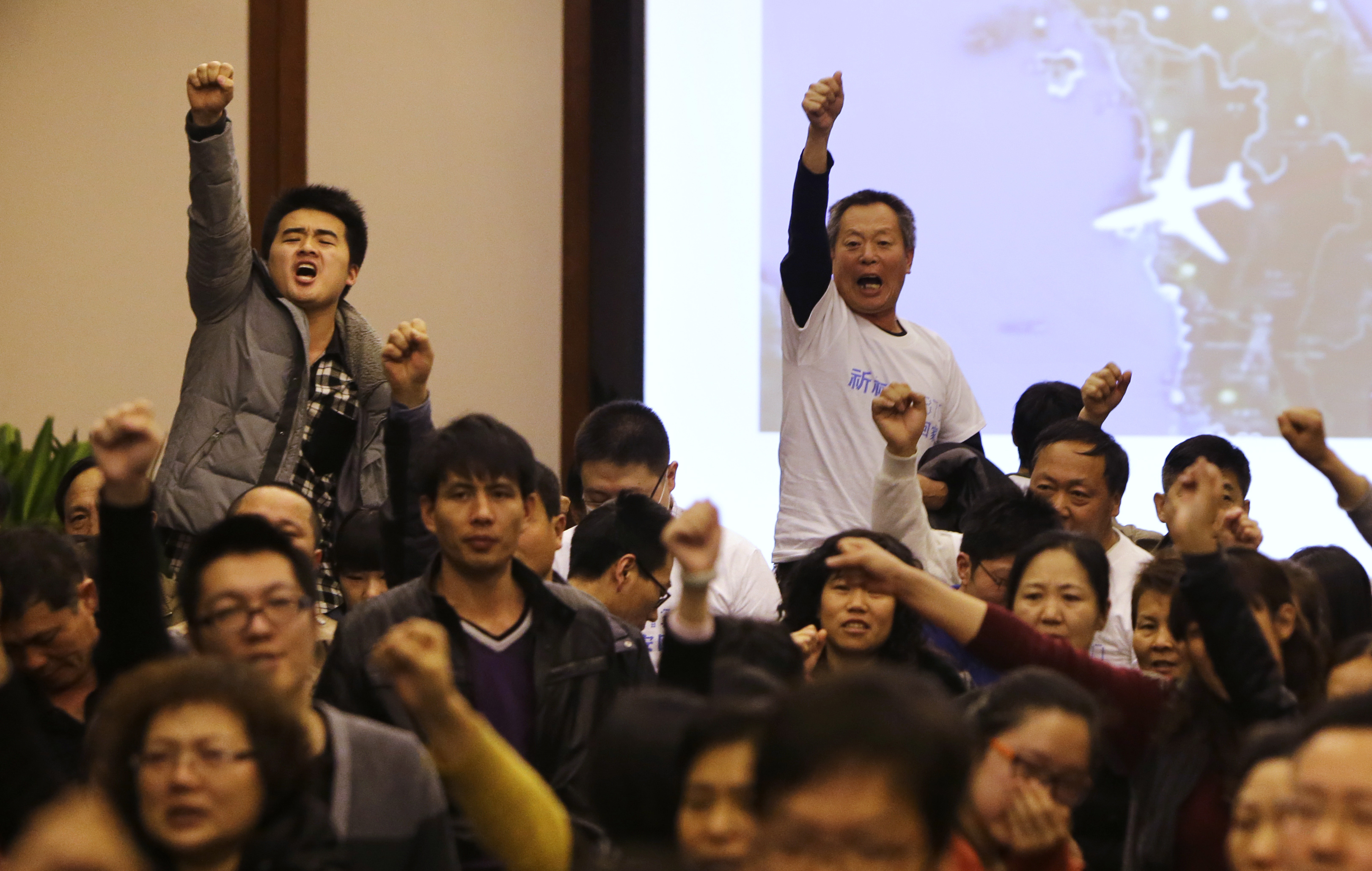 Family members of the Chinese passengers on board MH370 show their anger at a meeting with the airline
