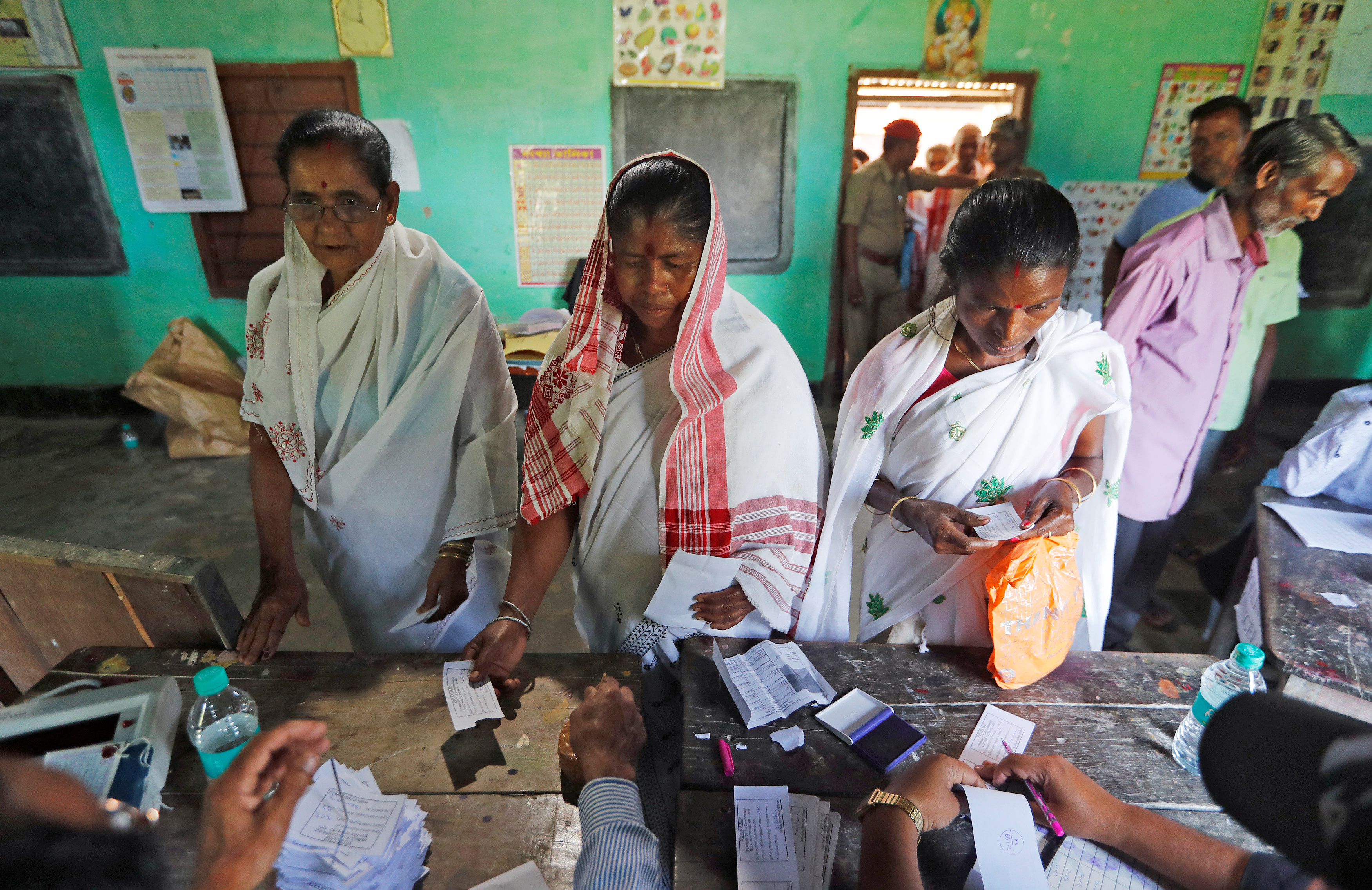 Women wait to collect their voter slips before casting their votes at a polling station during the first phase of general election in Majuli, a large river island in the Brahmaputra river, in the northeastern Indian state of Assam, India April 11, 2019. REUTERS/Adnan Abidi