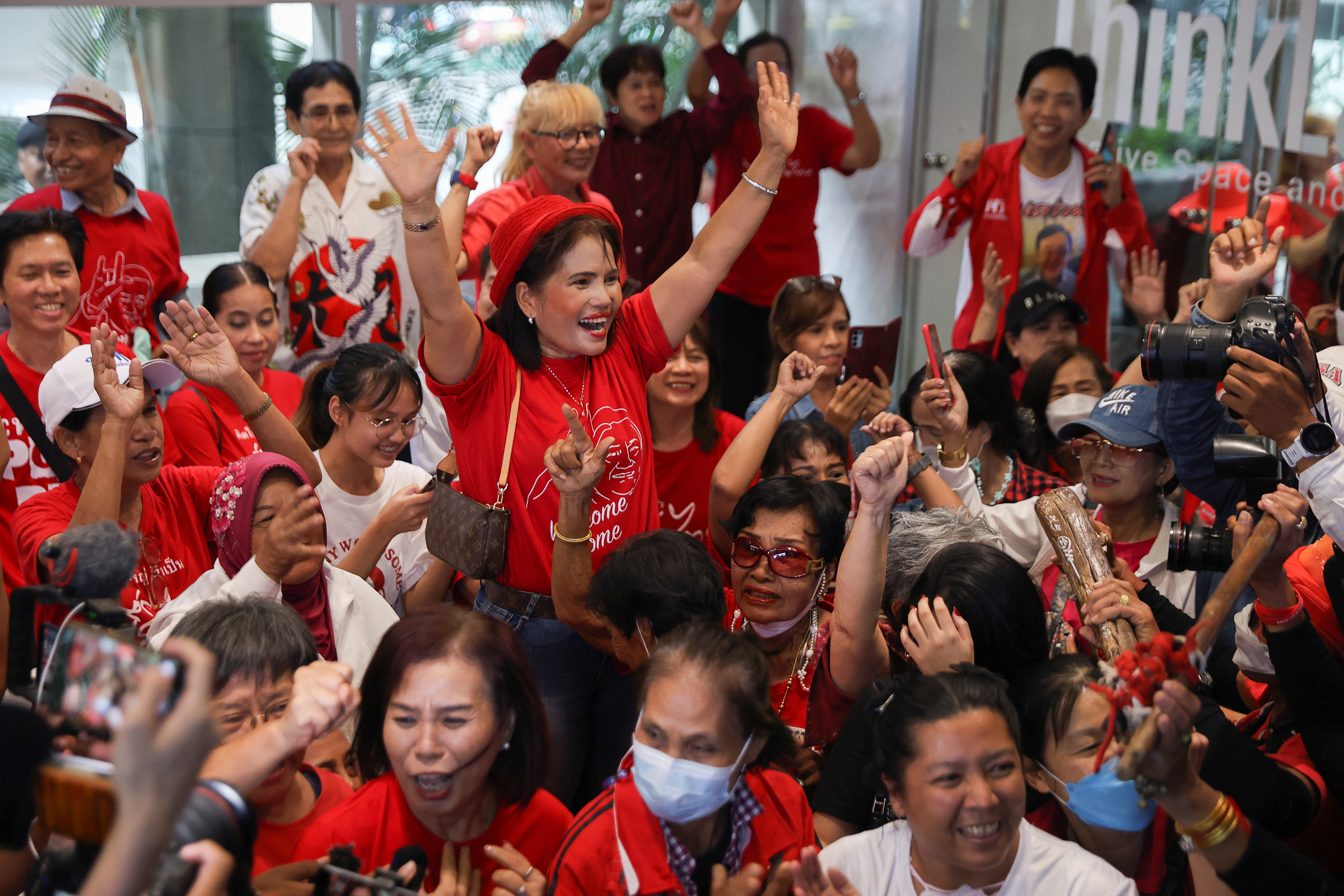 Pheu Thai supporters. They're wearing red and smiling and cheering.