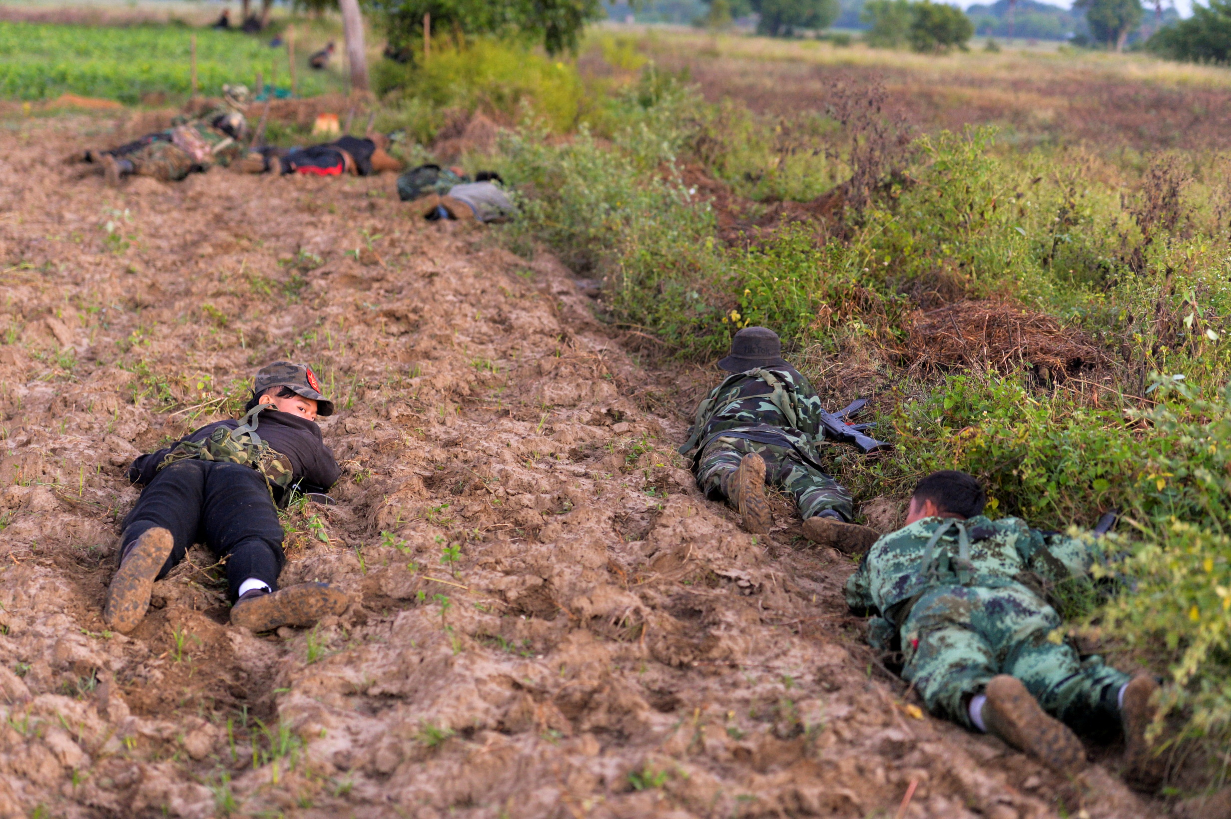Anti-coup fighters crawl on the ground as they battle the military in Sagaing. They are fighting in agricultural fields.
