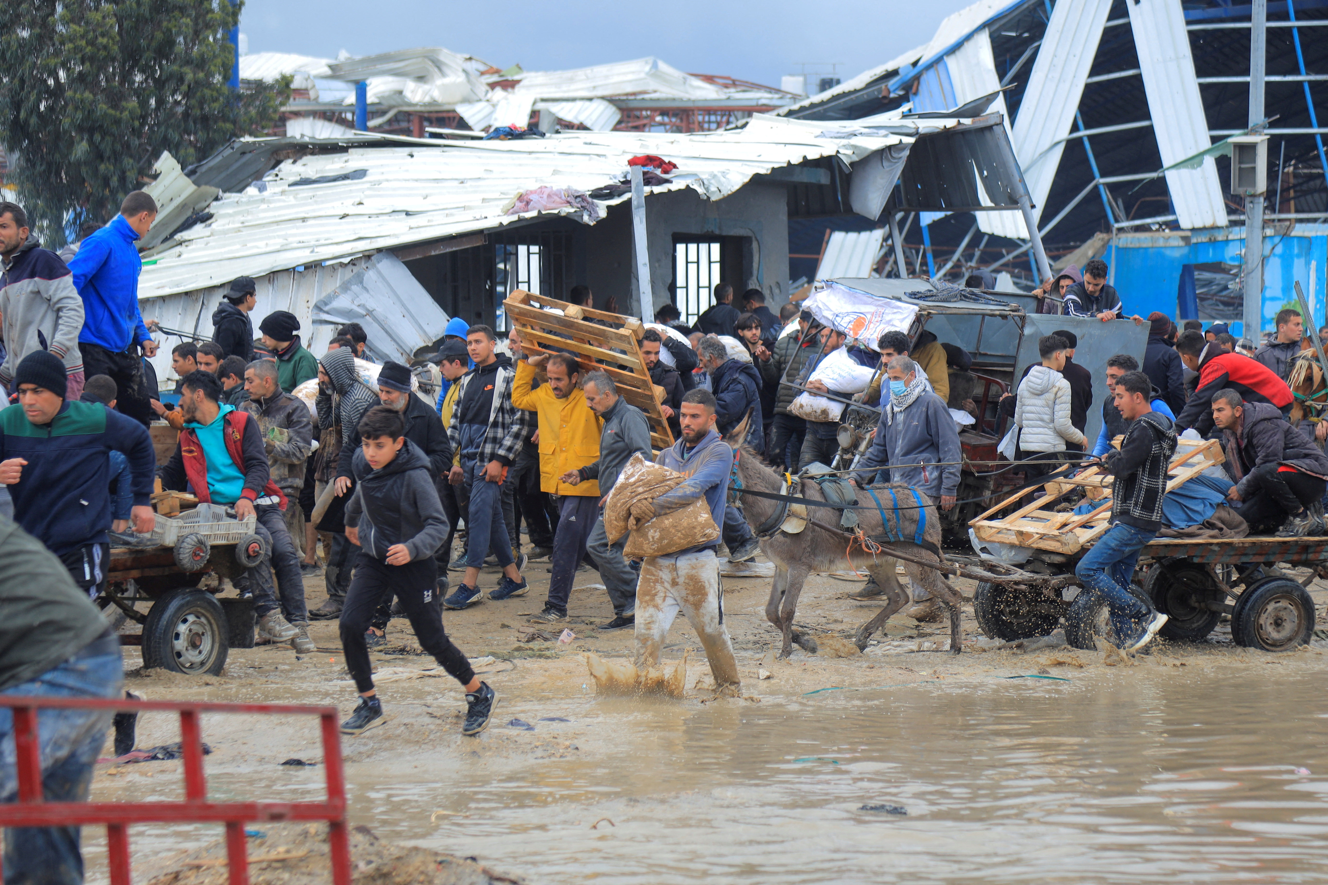 Hungry Palestinians carry bags of flour past destroyed buildings in Gaza City