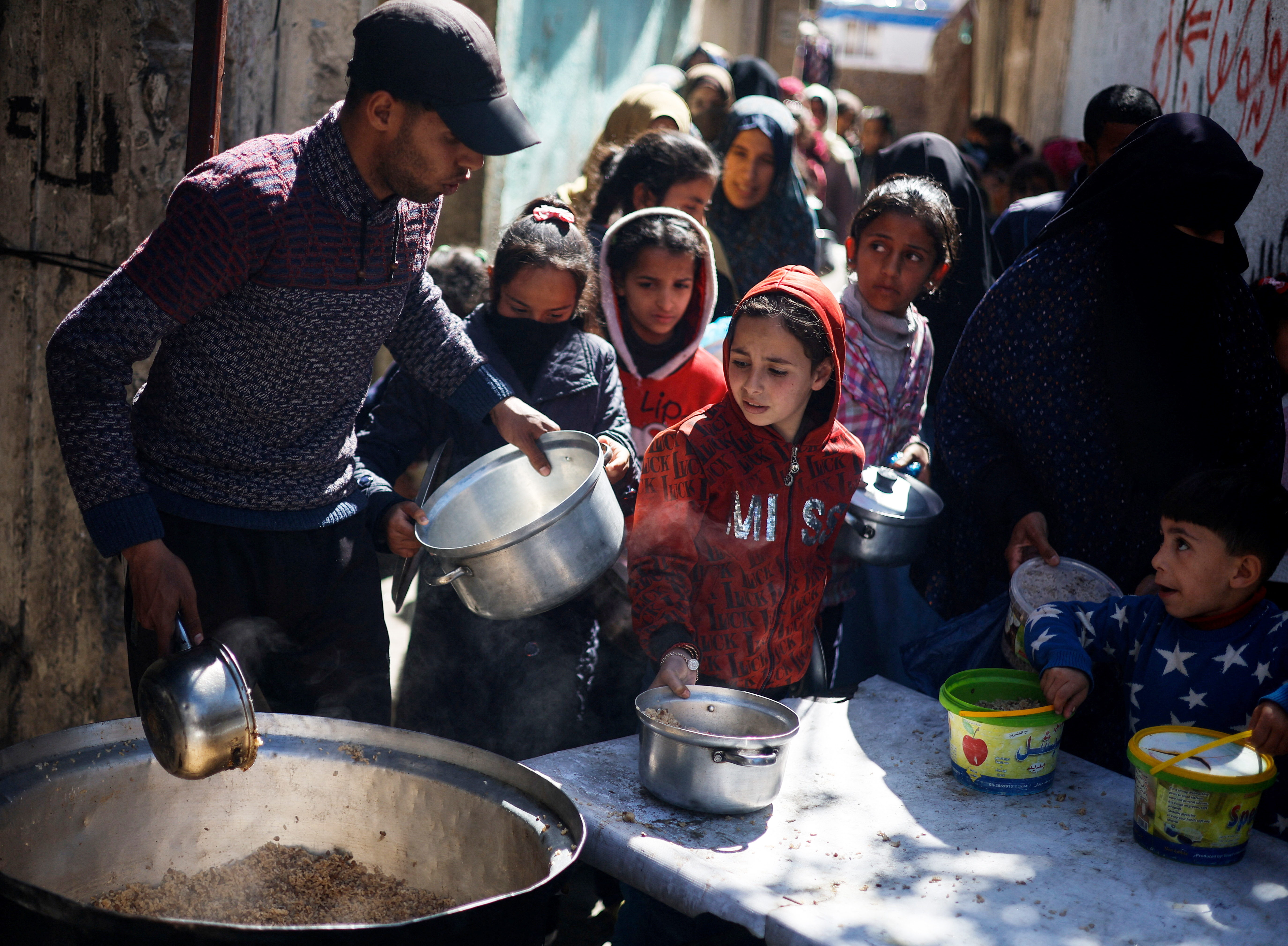 Palestinian children wait to receive food cooked by a charity kitchen amid shortages of food supplies, as the ongoing conflict between Israel and the Palestinian Islamist group Hamas continues, in Rafah, in the southern Gaza Strip, March 5, 2024. REUTERS/Mohammed Salem