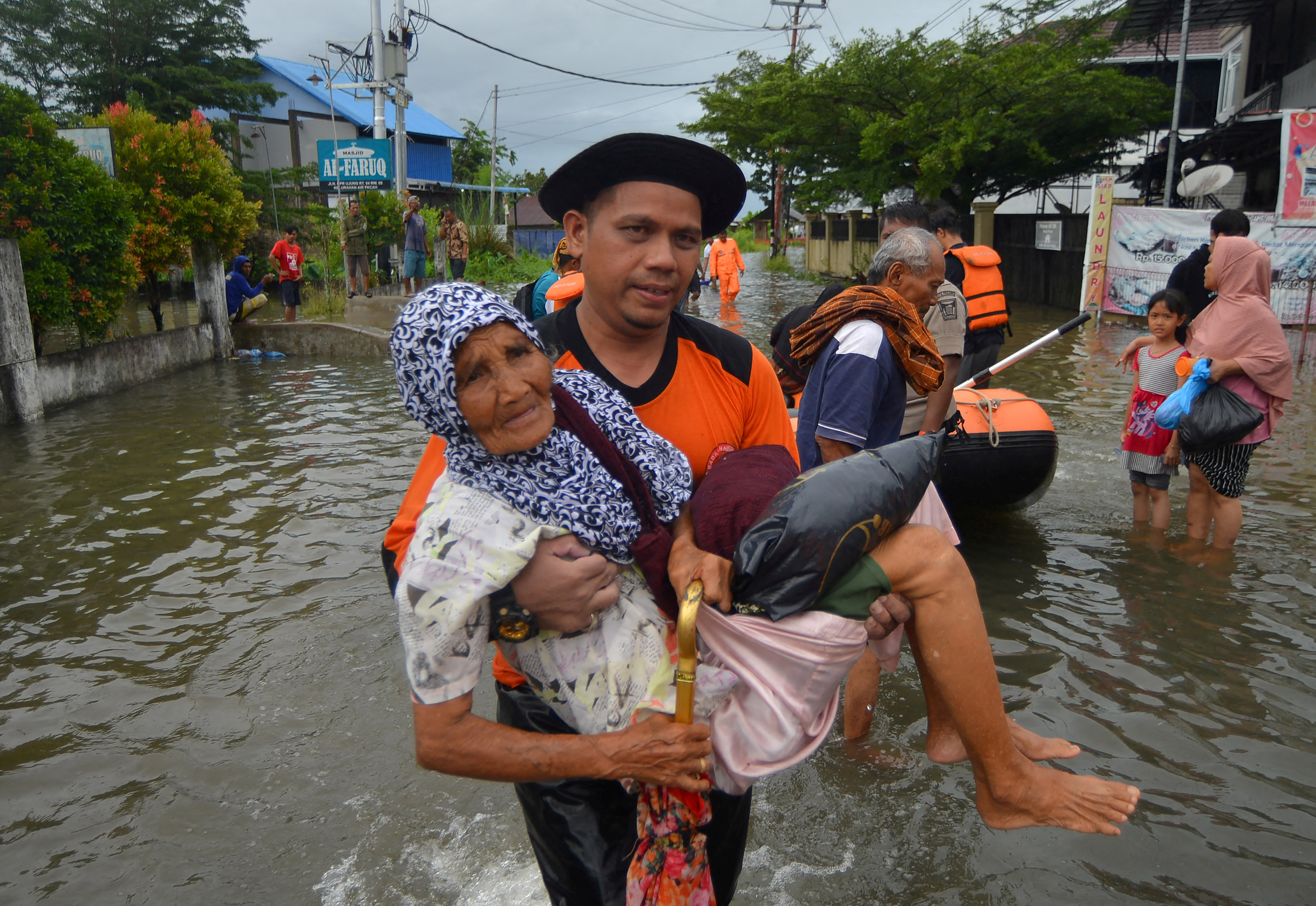 A Local Disaster Management Agency (BPBD) officer evacuates an elderly woman from a residential area affected by floods due to heavy rains, in Padang