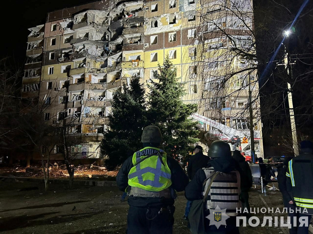 Police officers stand in a front of an apartment building damaged by a Russian missile strike