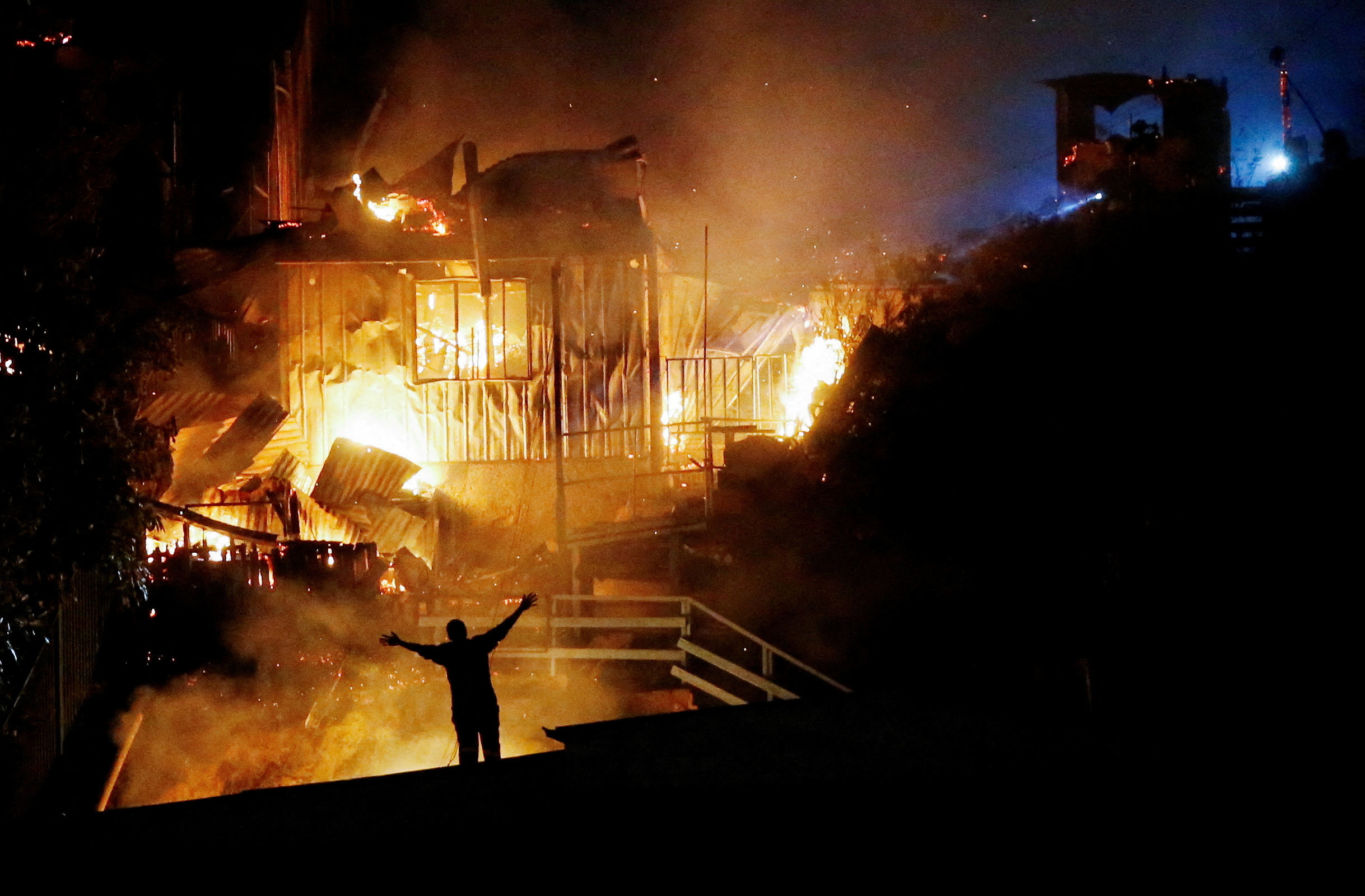 A person reacts as houses burn amid a wildfire in Valparaiso, Chile March 13