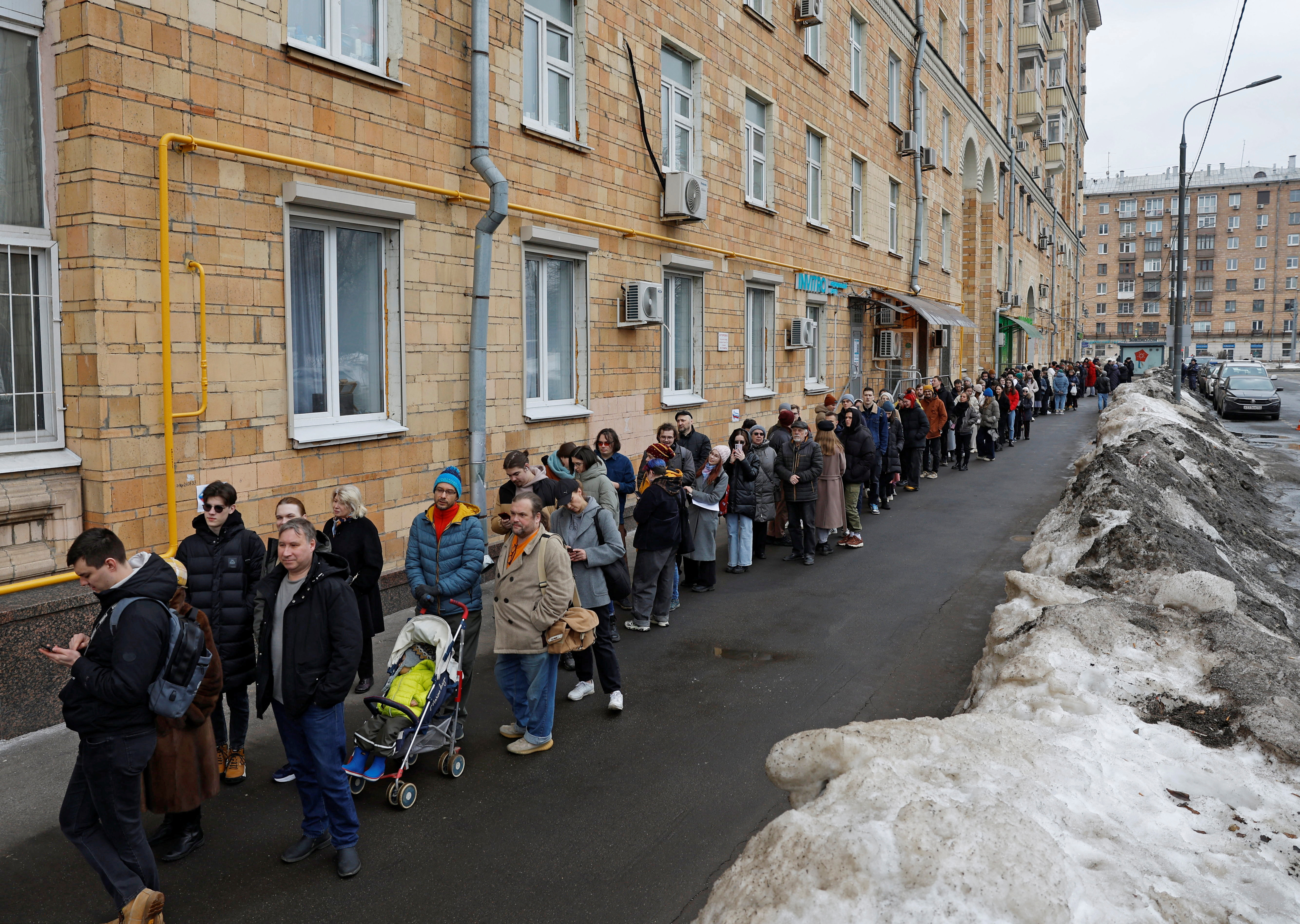 People stand in a line to enter a polling station around noon on the final day of the presidential election in Moscow, Russia, March 17,