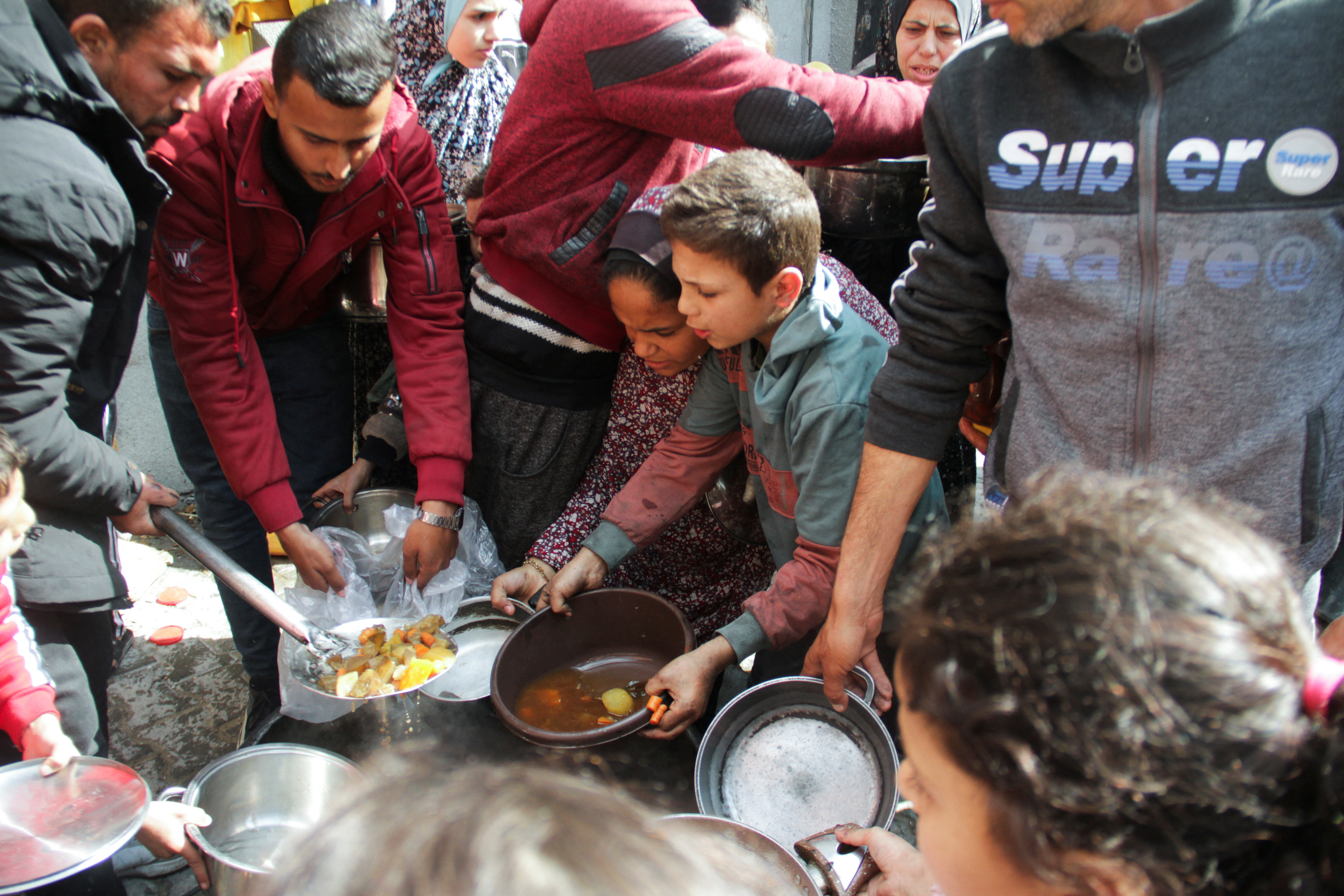 Palestinians gather to receive free food as Gaza residents face crisis levels of hunger, during the holy month of Ramadan