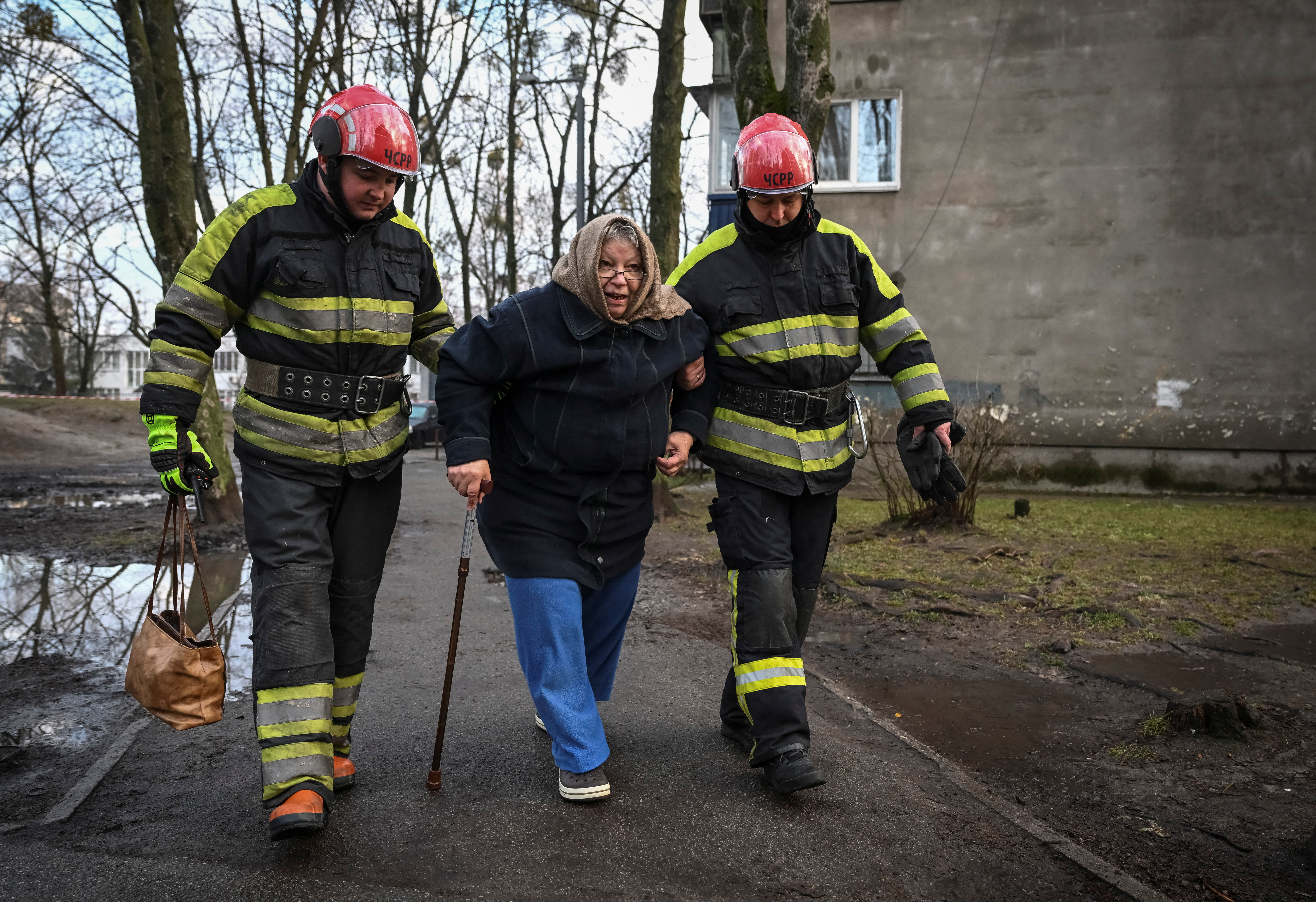 Rescuers help a local resident who leaves the site of a residential building damaged during a Russian missile attack