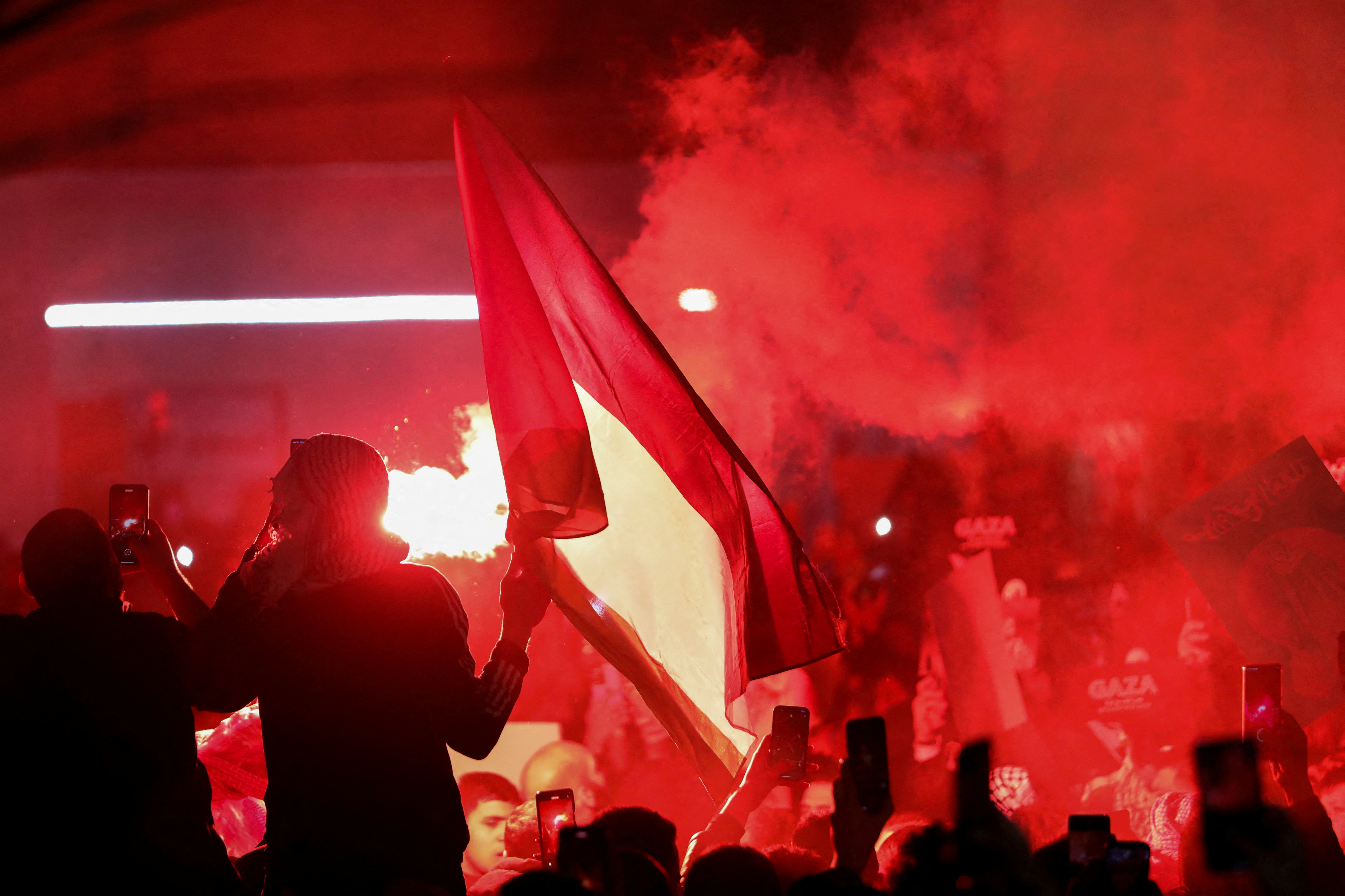 Demonstrators carry banners and flags as a flare burns during a protest in support of Palestinians in Gaza, amid the ongoing conflict between Israel and the Palestinian Islamist group Hamas, outside Al Kalouti mosque near the Israeli embassy in Amman, Jordan, March 27, 2024. REUTERS/Alaa Al-Sukhni REFILE - CORRECTING FROM "FIRE" TO "FLARE