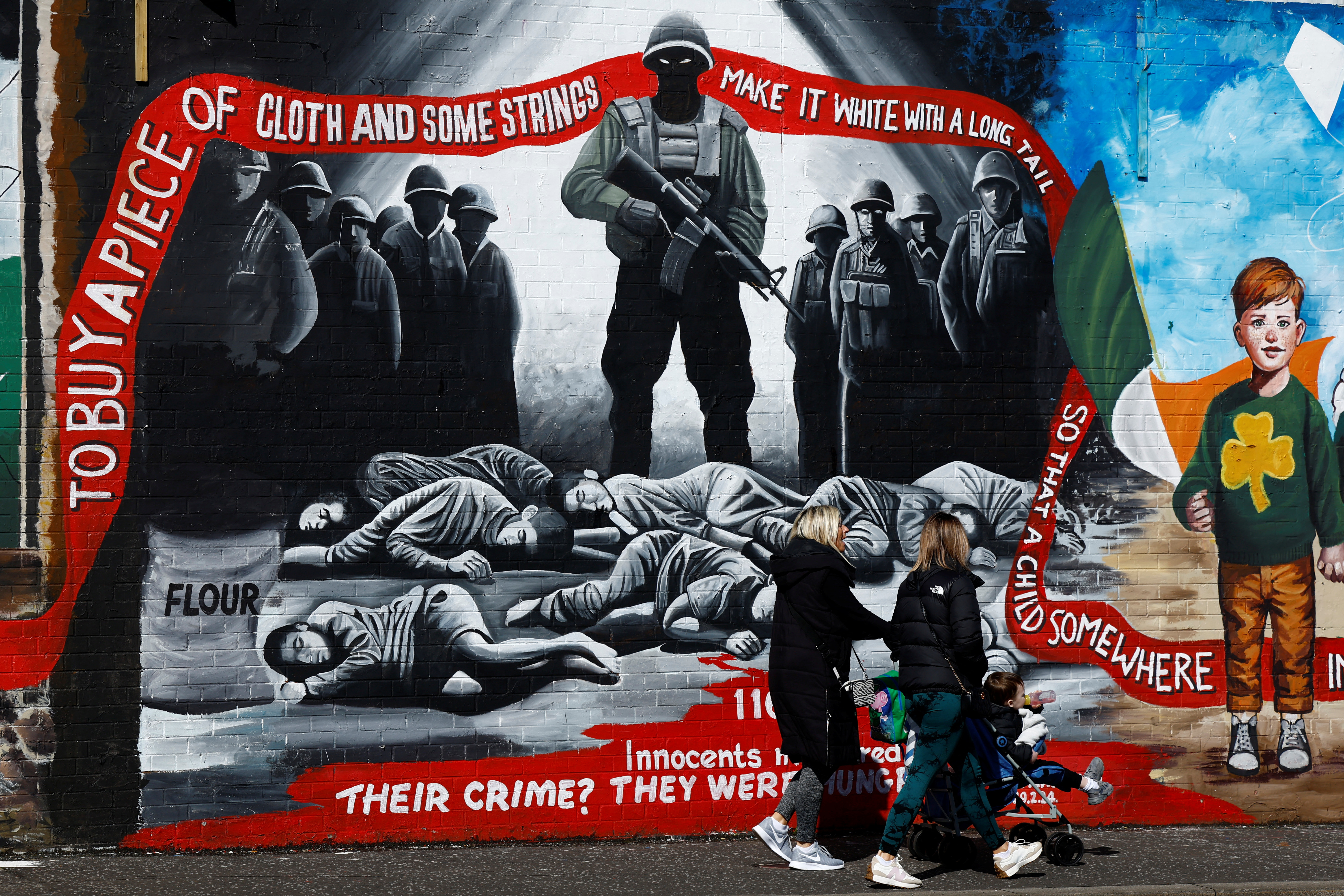 People walk past pro-Palestinian murals on the International Wall in support of Gaza, amid the ongoing conflict between Israel and the Palestinian Islamist group Hamas, in Belfast, Northern Ireland, March 29