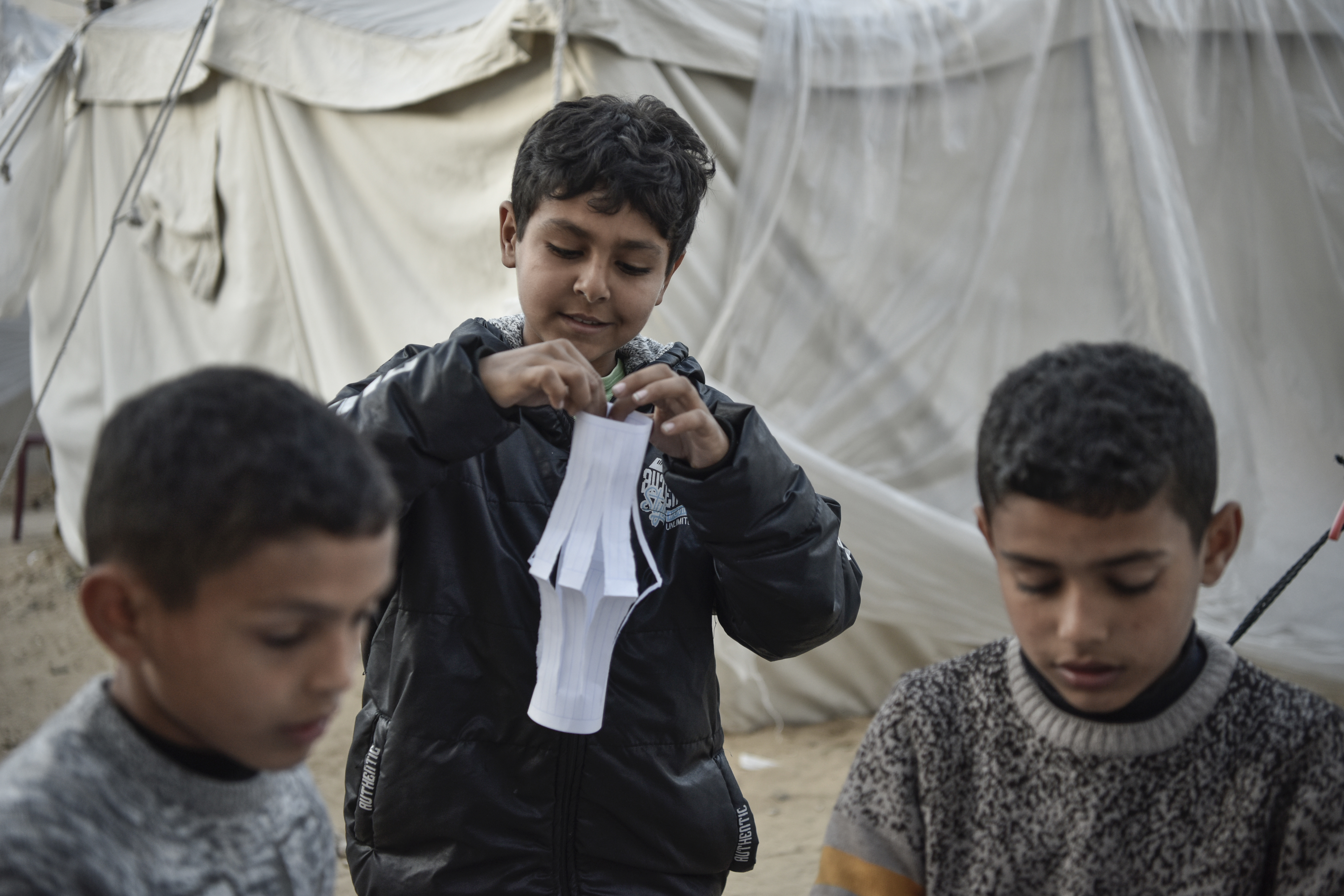 Palestinian children make Ramadan lanterns out of paper and hang them in their makeshift tents ahead of the holy month of Ramadan in Rafah