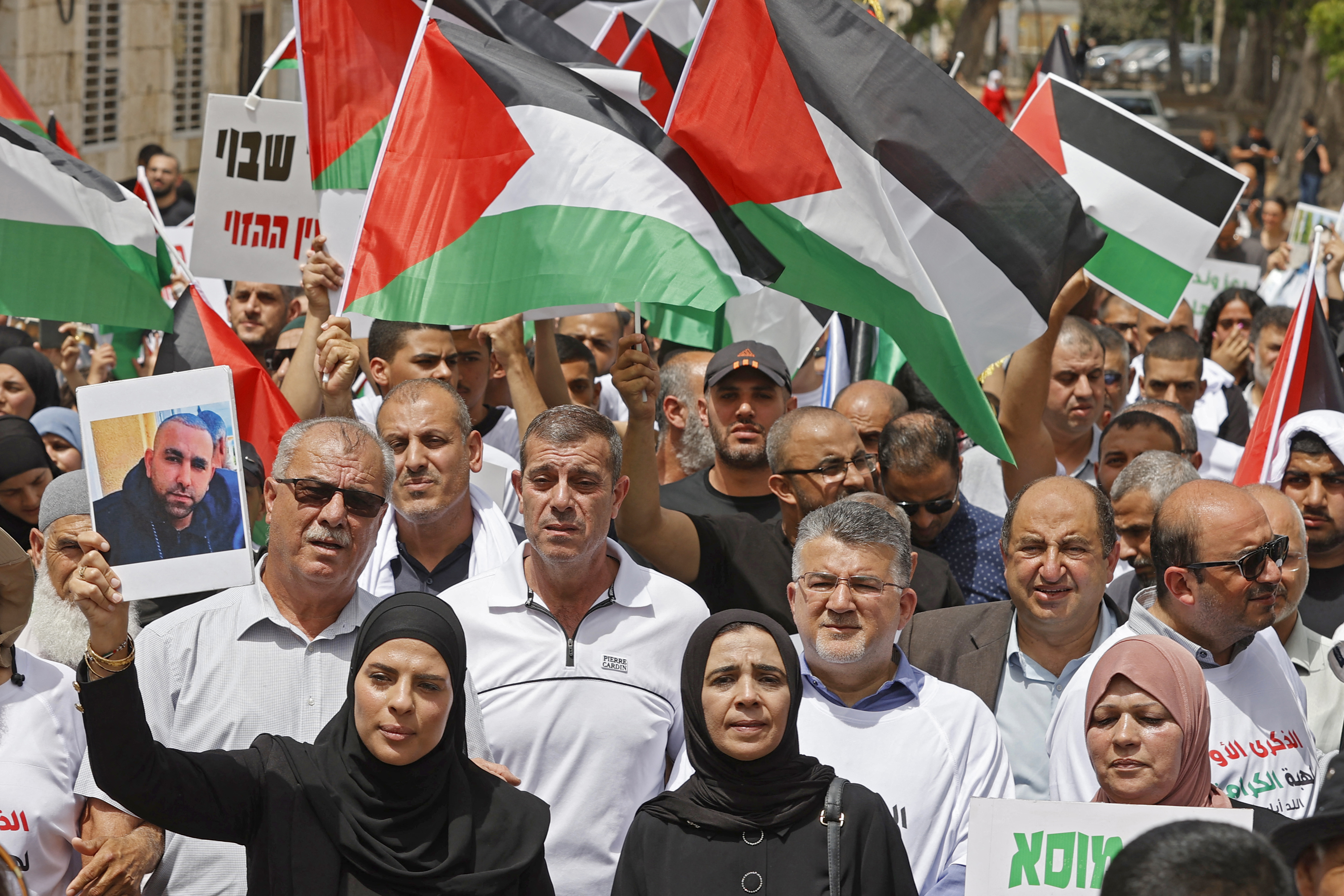 Arab Israelis rally with Palestinian flags in the mixed city of Lod near Tel Aviv on May 13, 2022, a year after a member of their community was killed during intercommunal violence. (Photo by JACK GUEZ / AFP)