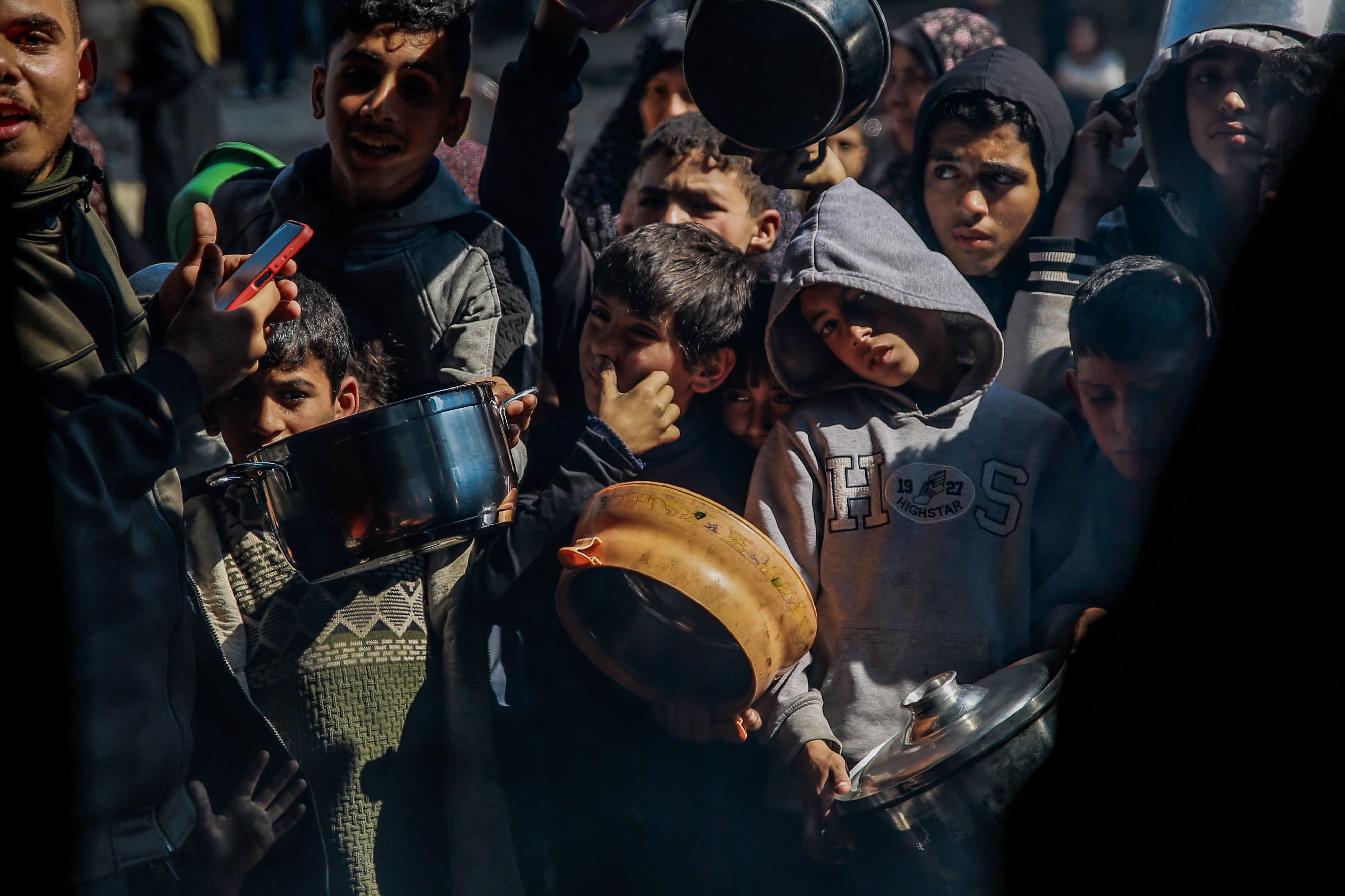 Palestinian children wait to get food from an aid distribution team in Beit Lahia, northern Gaza, on February 26