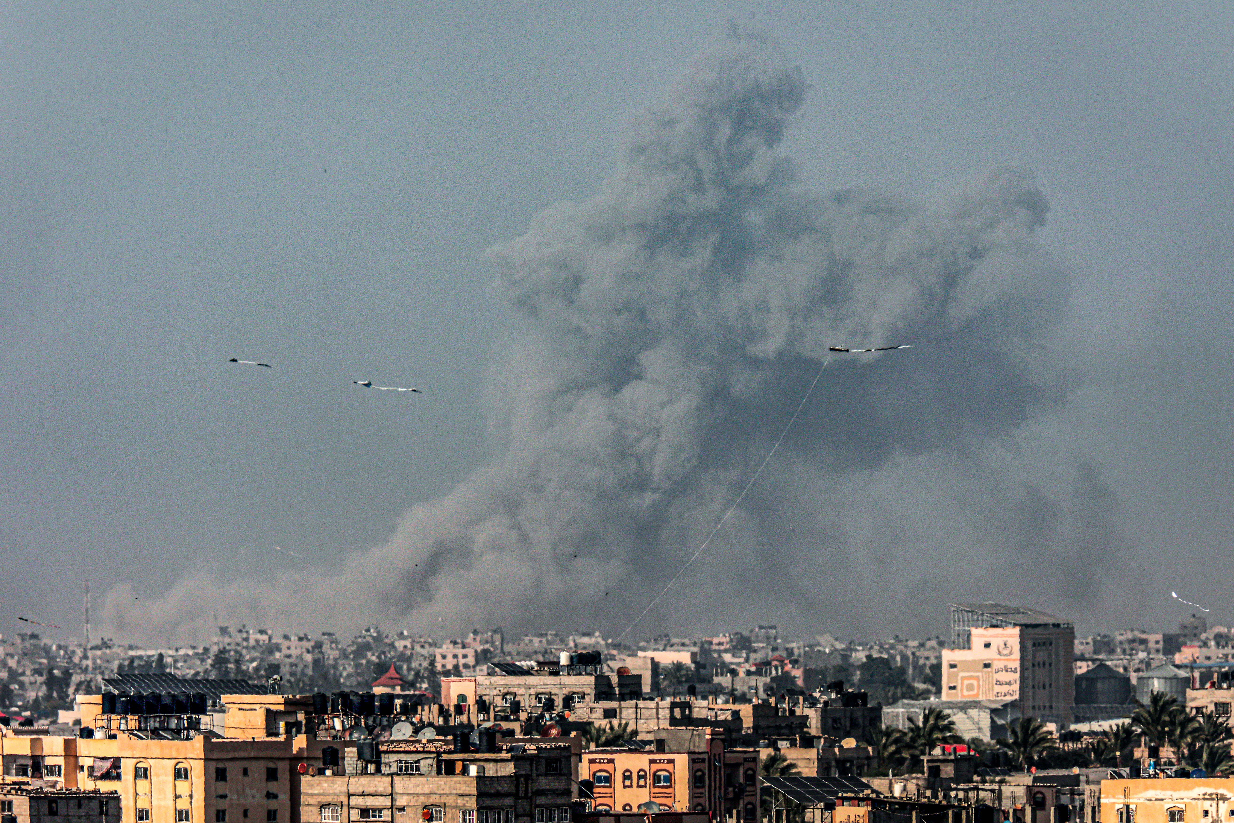 Kites fly in Rafah as a smoke plume erupts during Israeli bombardment on Khan Yunis in the southern Gaza Strip on March 29