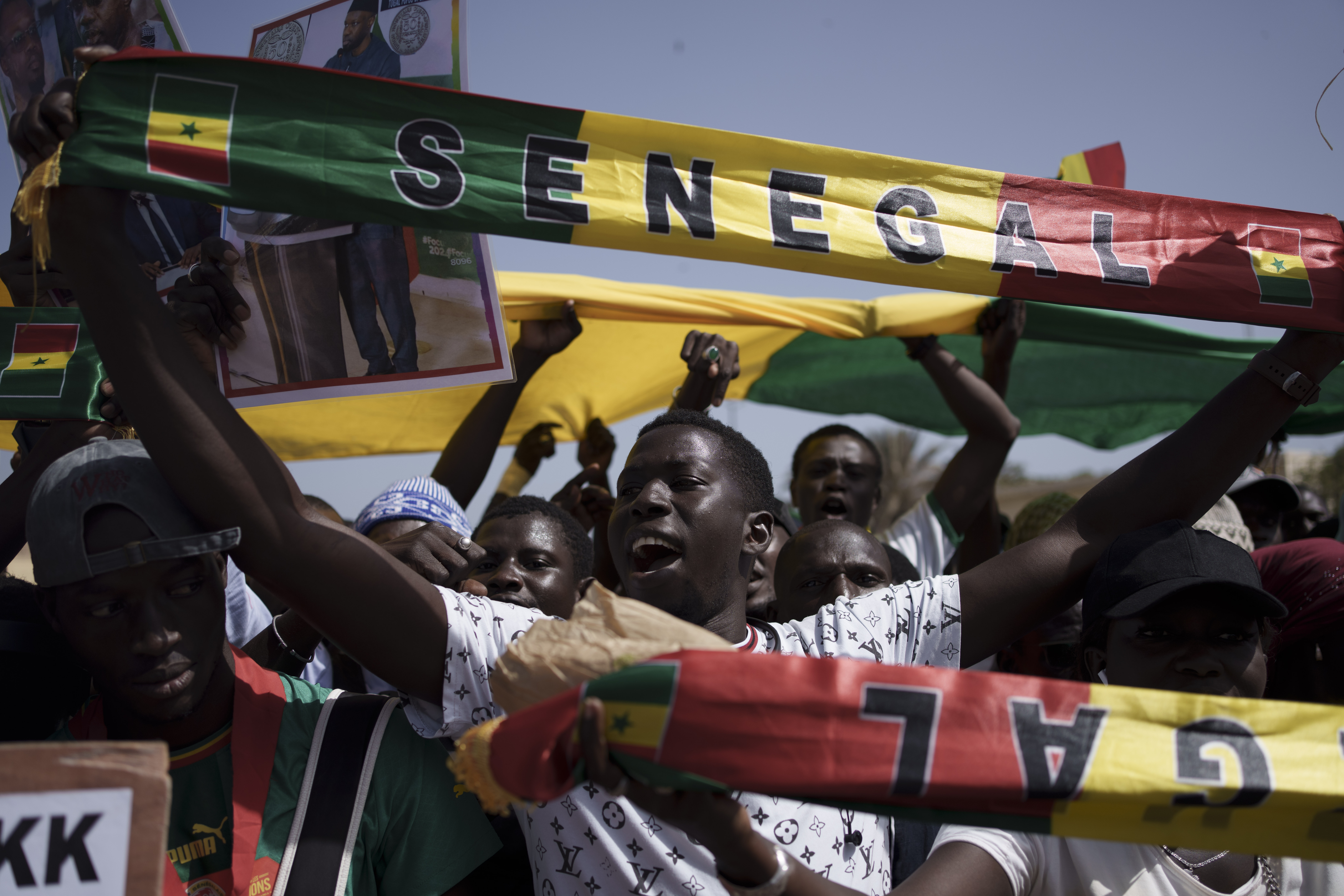 People hold a banner in the colours of Senegal's flag