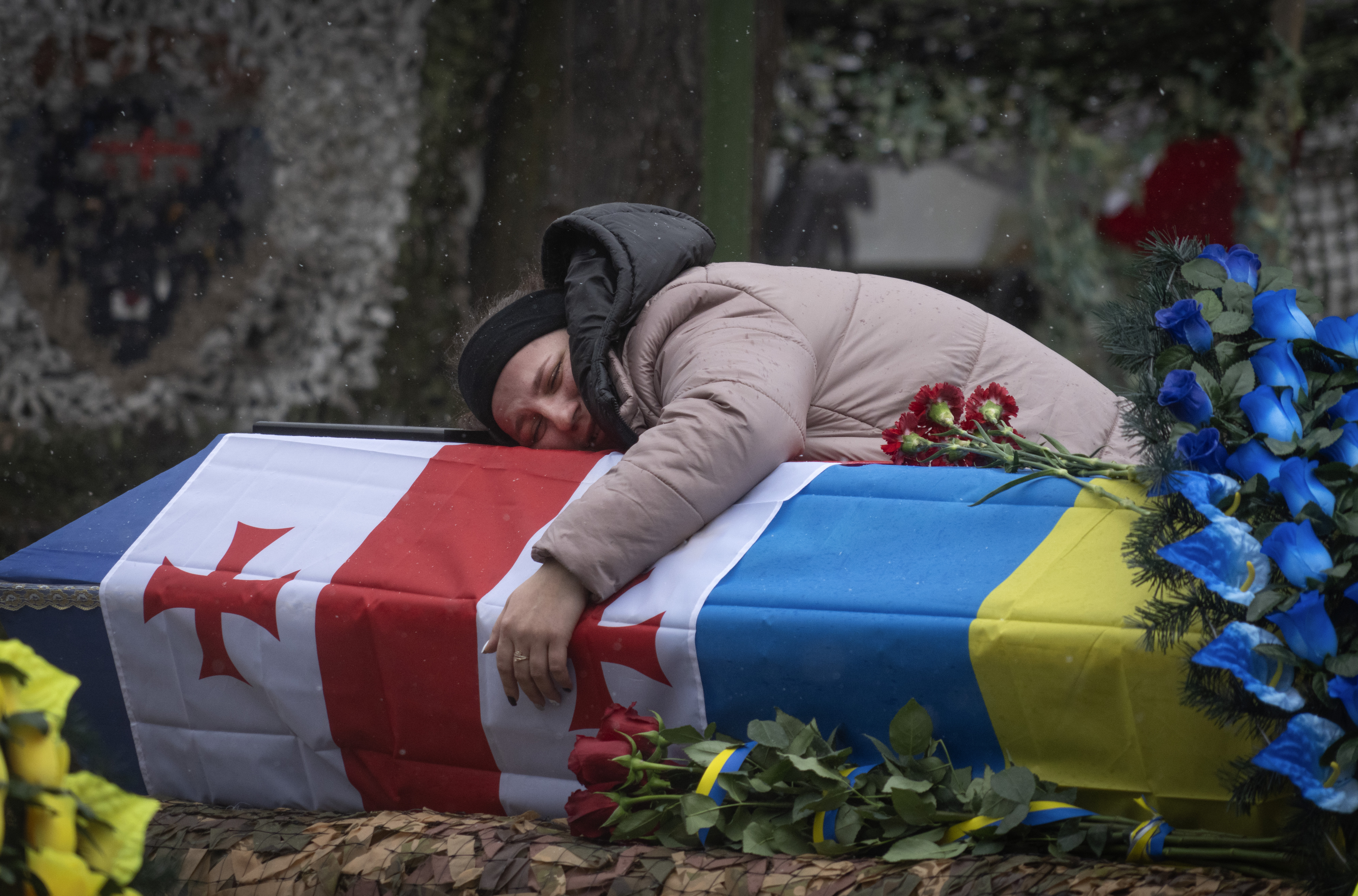 A relative mourns over a coffin of Nodar Nasirov, 28, a volunteer of the Georgian legion who was killed in a battle against Russian troops, during a funeral ceremony in Kyiv, Ukraine, Tuesday, March 12