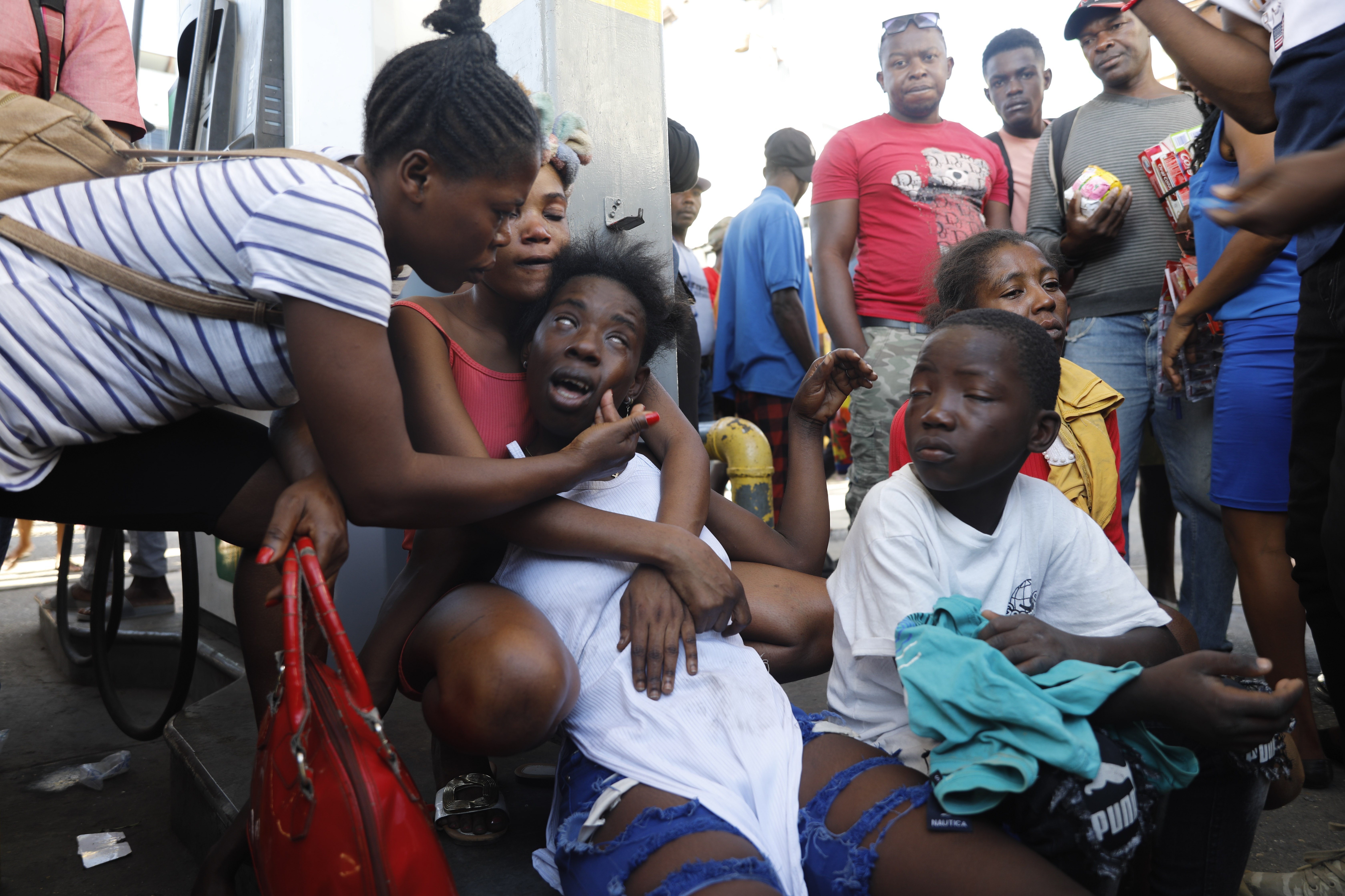 The relative of a person found dead in the street reacts after an overnight shooting in the Petion Ville