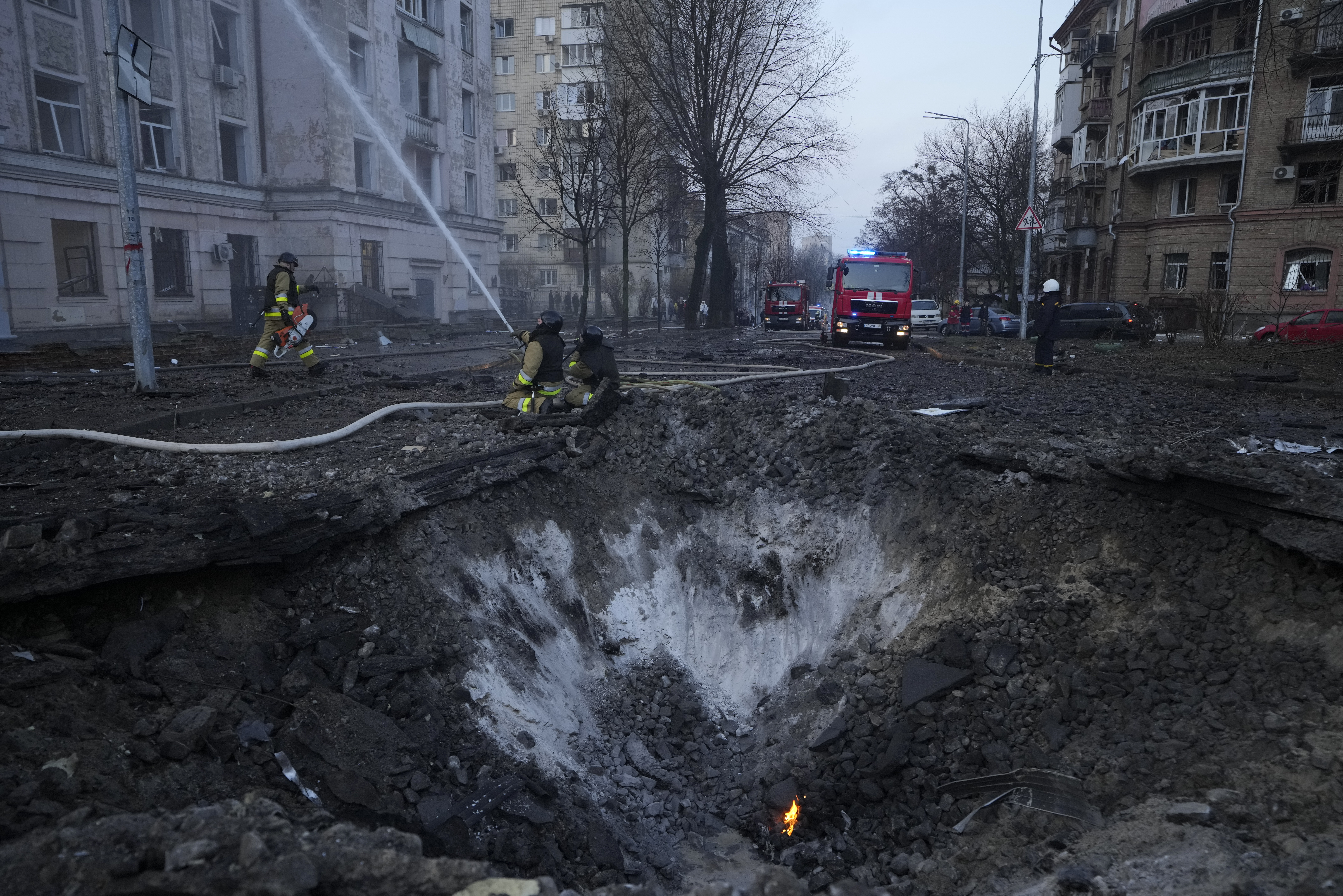 Firefighters work near the crater at the site after Russian attacks in Kyi