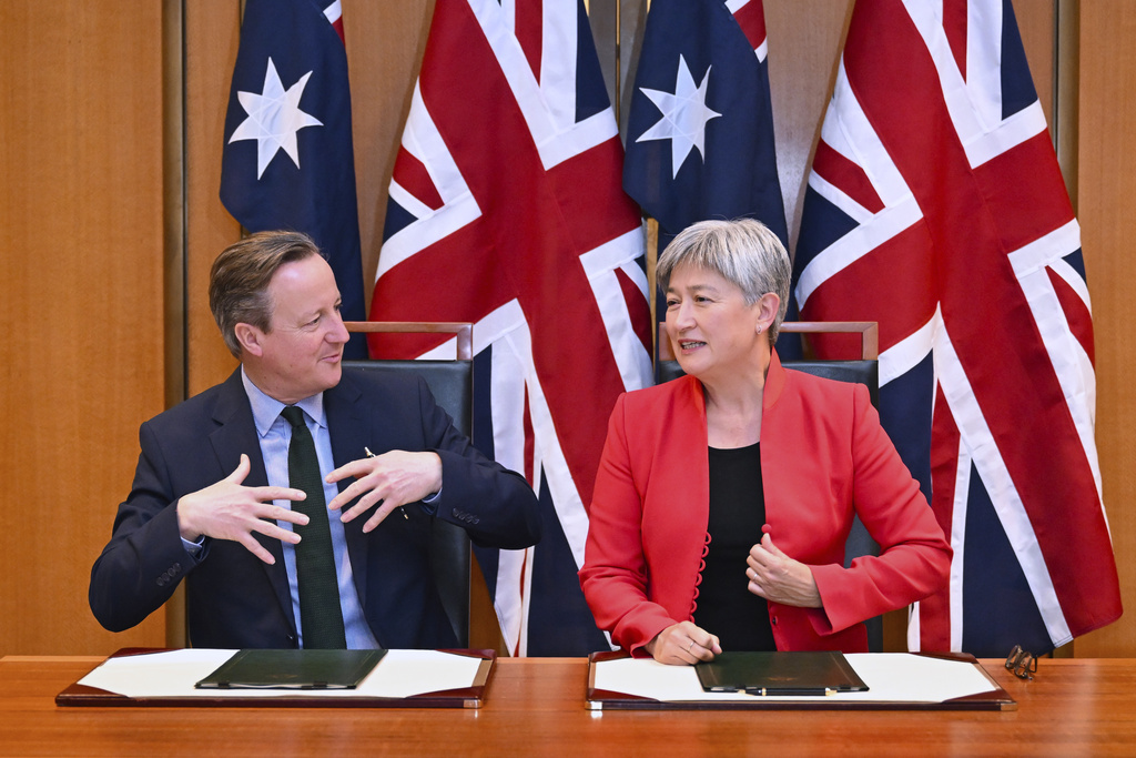 Britain's Foreign Secretary David Cameron, left, and Australian Foreign Minister Penny Wong exchange documents during a signing ceremony at Parliament House at Parliament House in Canberra