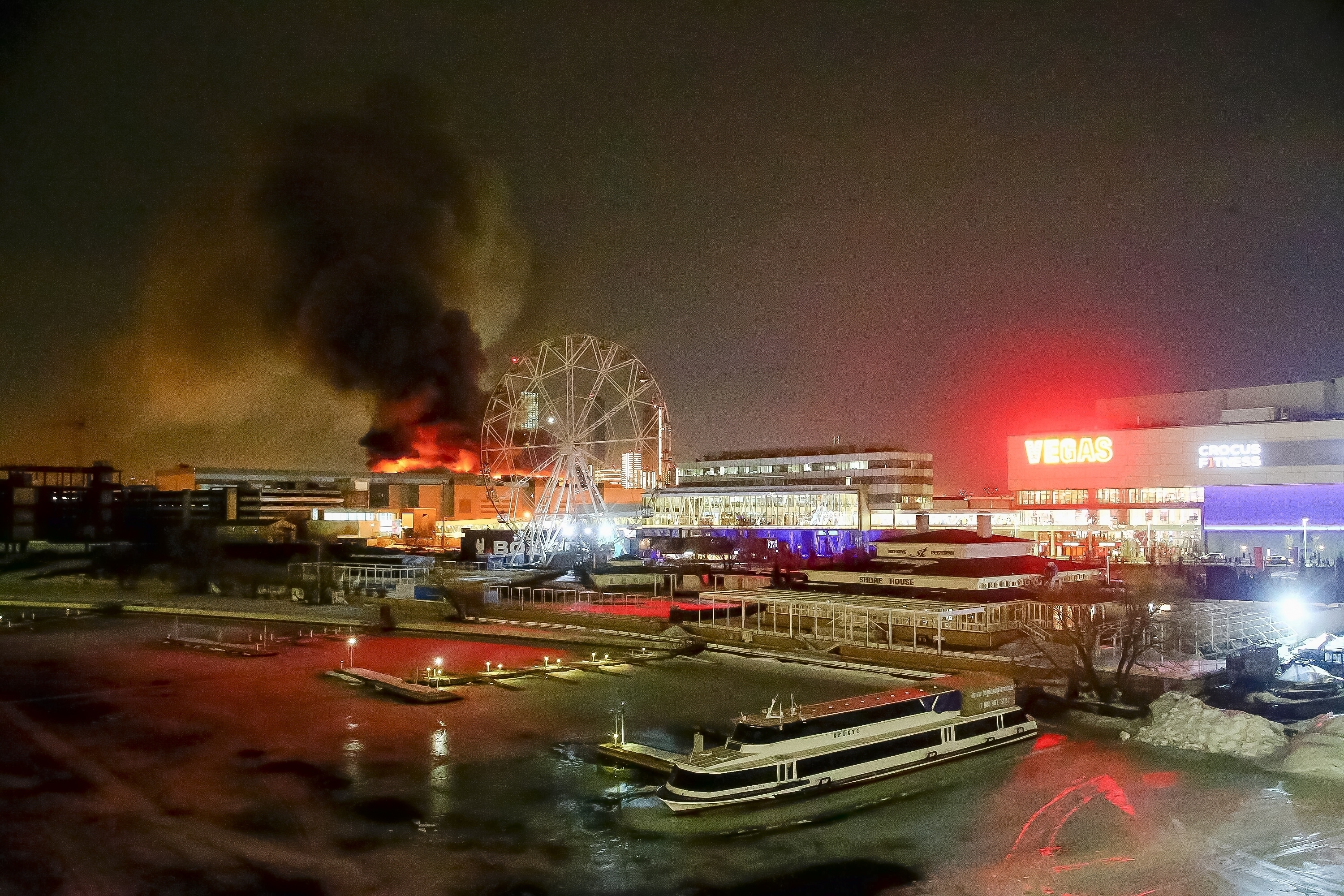 A wide view of the Crocus Concert Hall and its surroundings. The building is on fire.