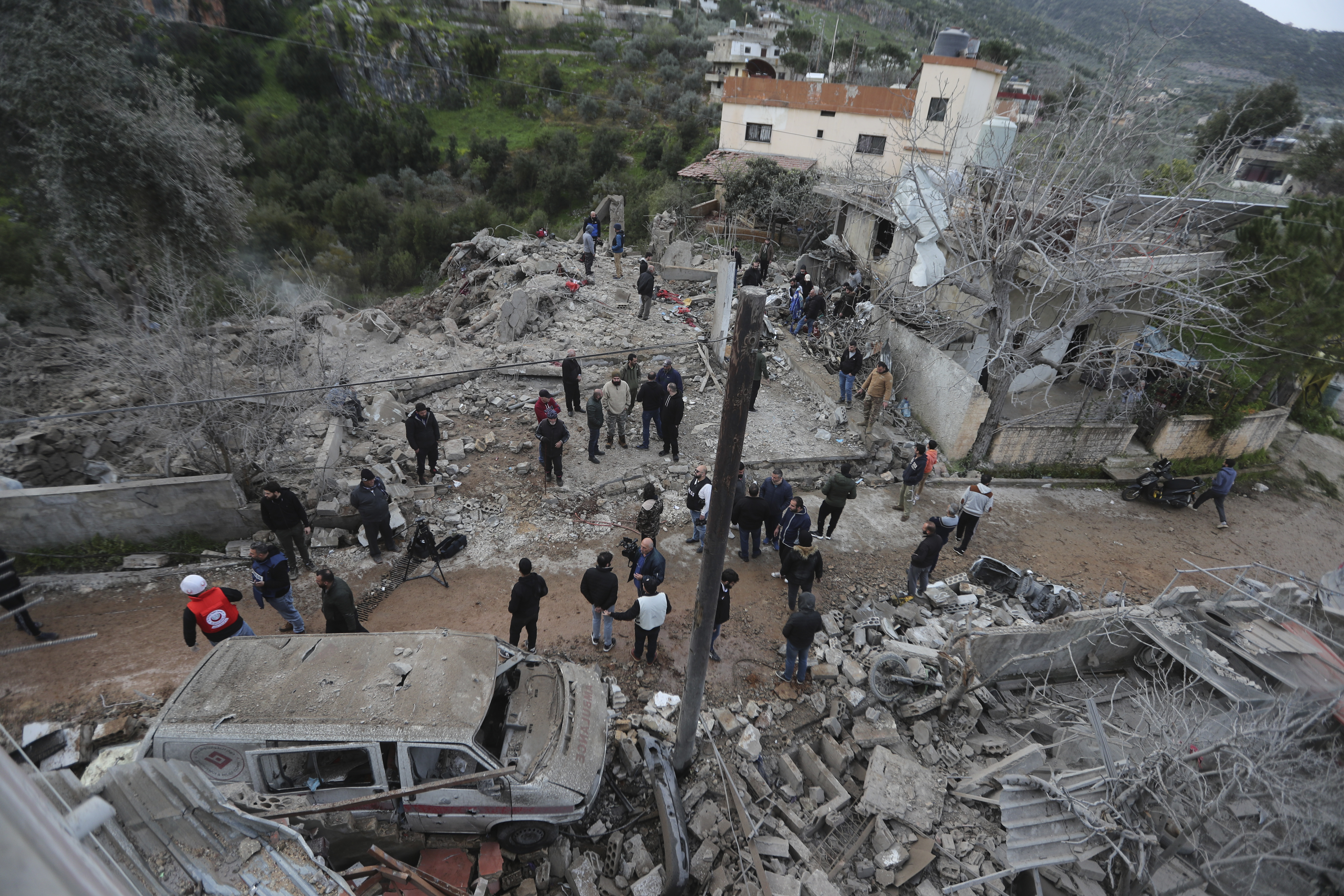 People gather on the rubble of a paramedic center that was destroyed by an Israeli airstrike early Wednesday in Hebbariye village, south Lebanon, Wednesday, March 27, 2024. The Israeli airstrike on a paramedic center linked to a Lebanese Sunni Muslim group killed several people of its members. The strike was one of the deadliest single attacks since violence erupted along the Lebanon-Israel border more than five months ago. (AP Photo/Mohammed Zaatari)