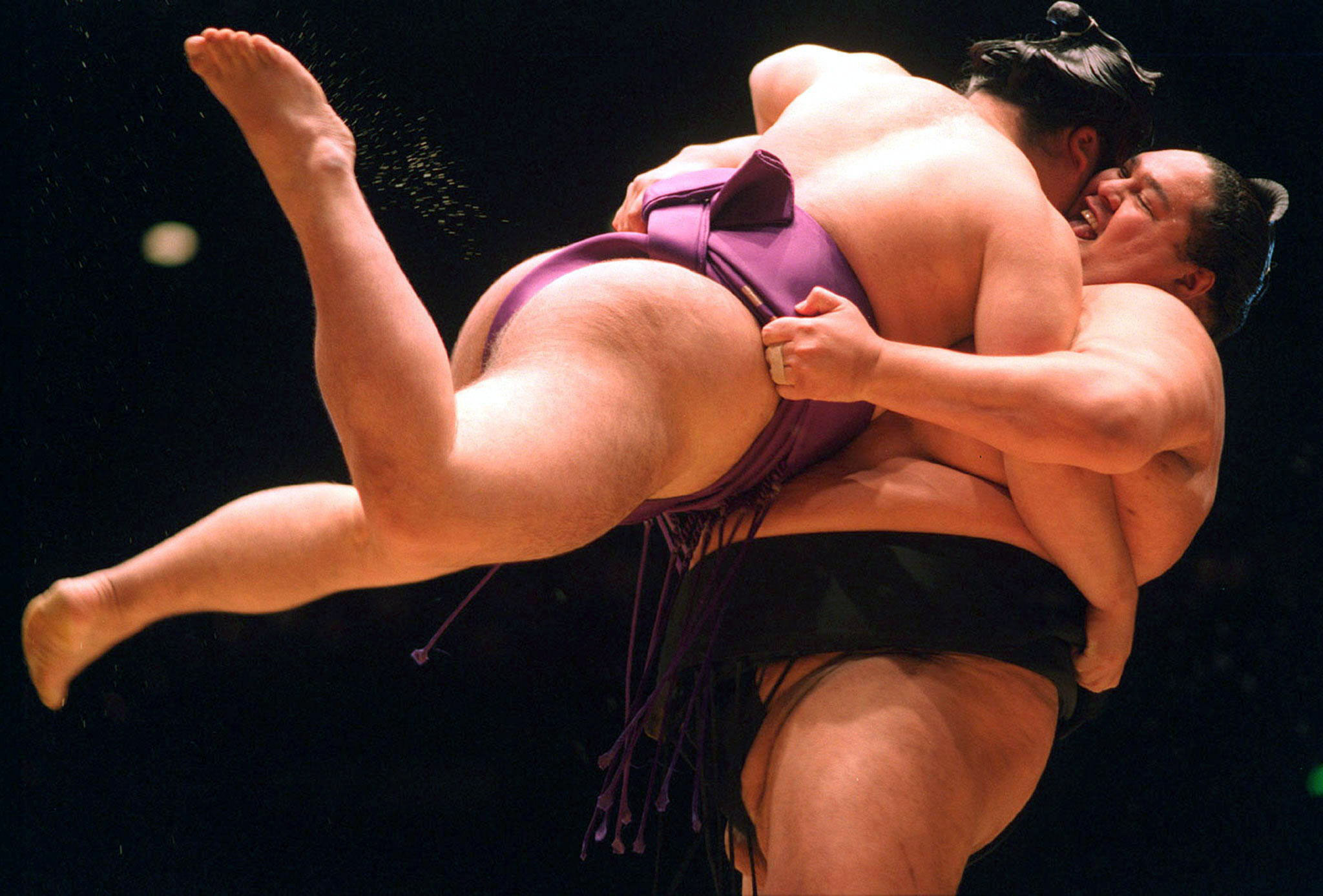 Sumo wrestler Akebono (R) has his opponent Kotonowaka airborne during a tournament.