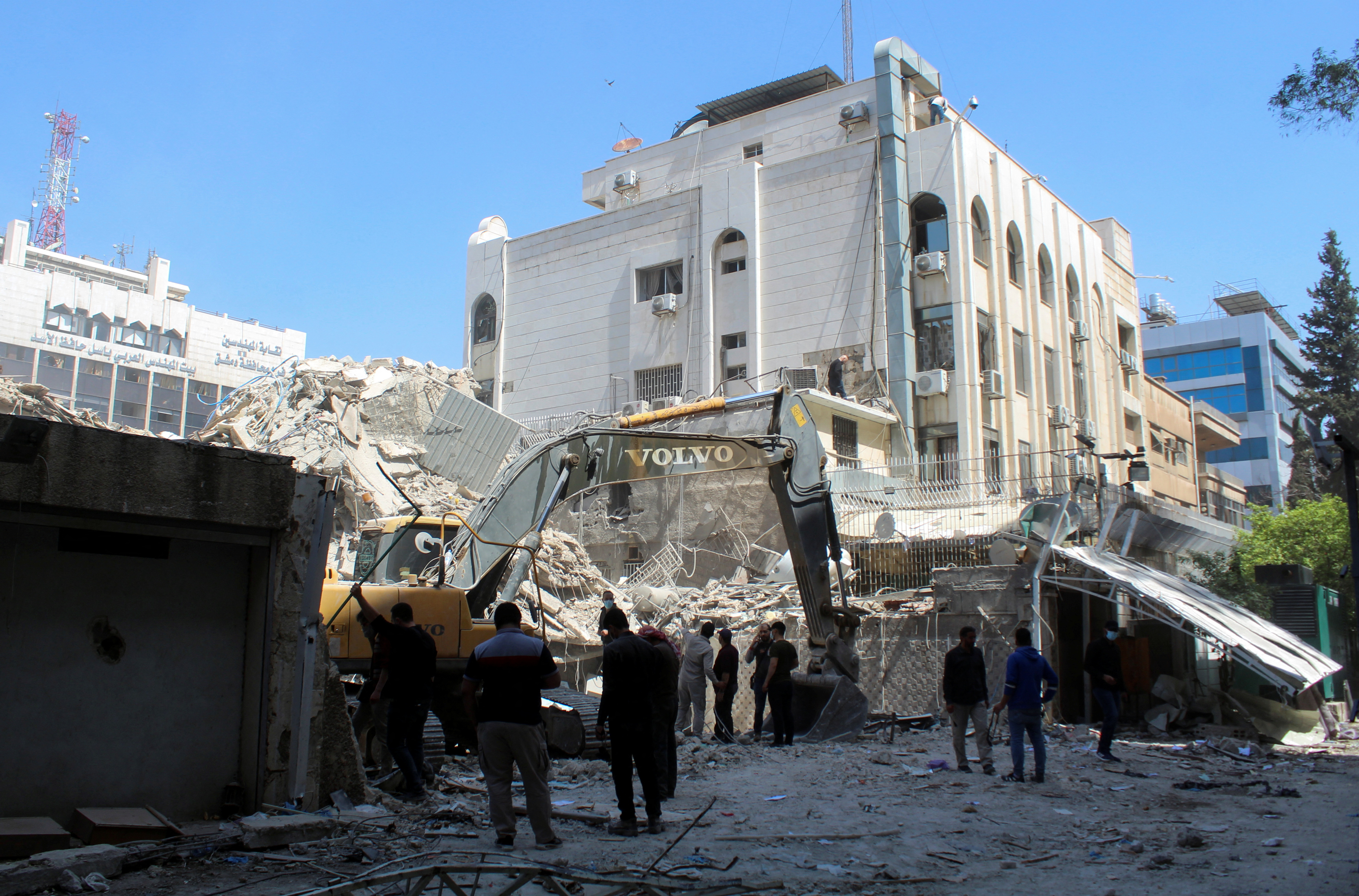 People gather as an excavator clears rubble after a suspected Israeli strike on Monday on Iran's consulate, adjacent to the main Iranian embassy building, which Iran said had killed seven military personnel including two key figures in the Quds Force, in the Syrian capital Damascus, Syria April 2, 2024. REUTERS/Firas Makdesi
