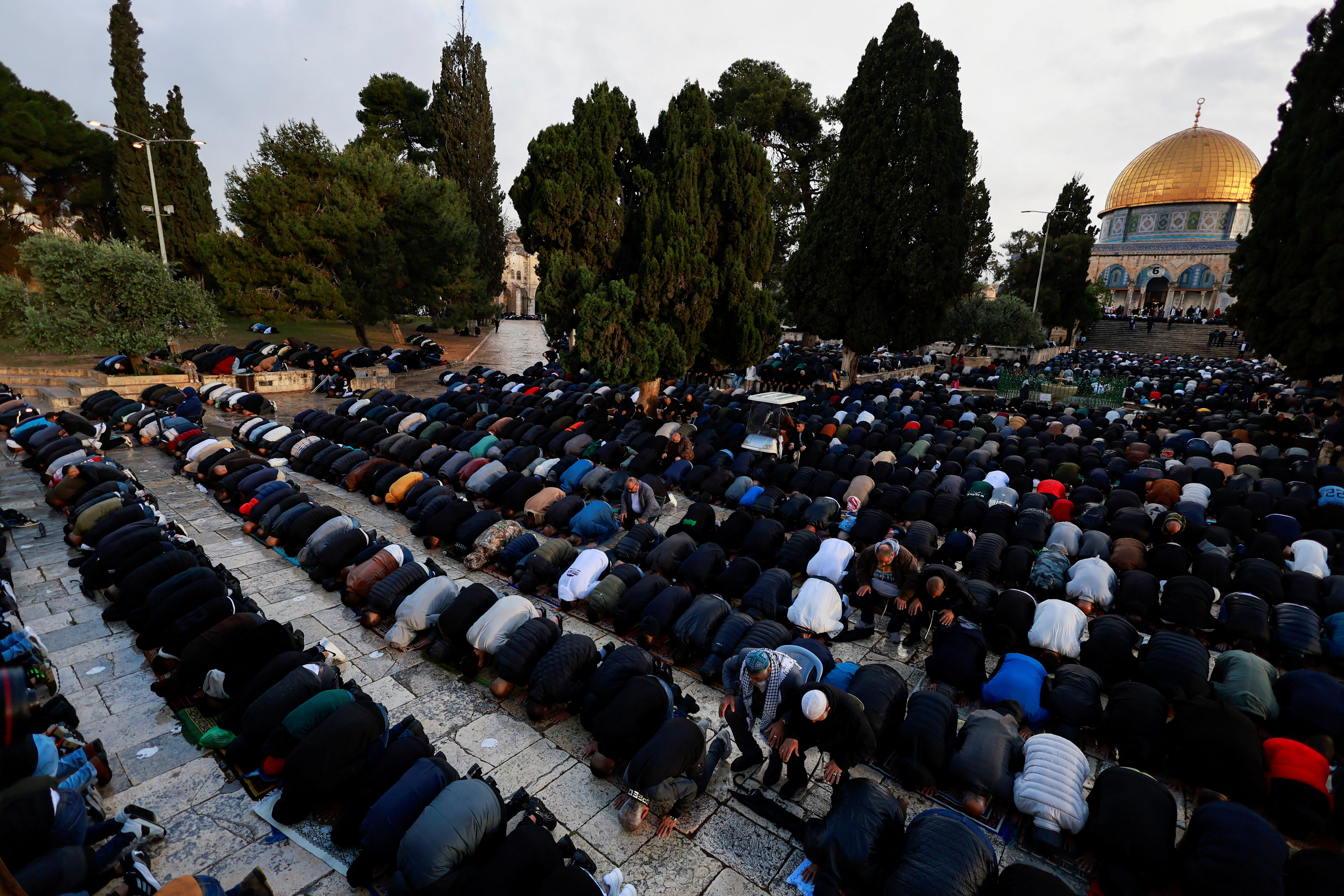 people pray in front of a gold dome