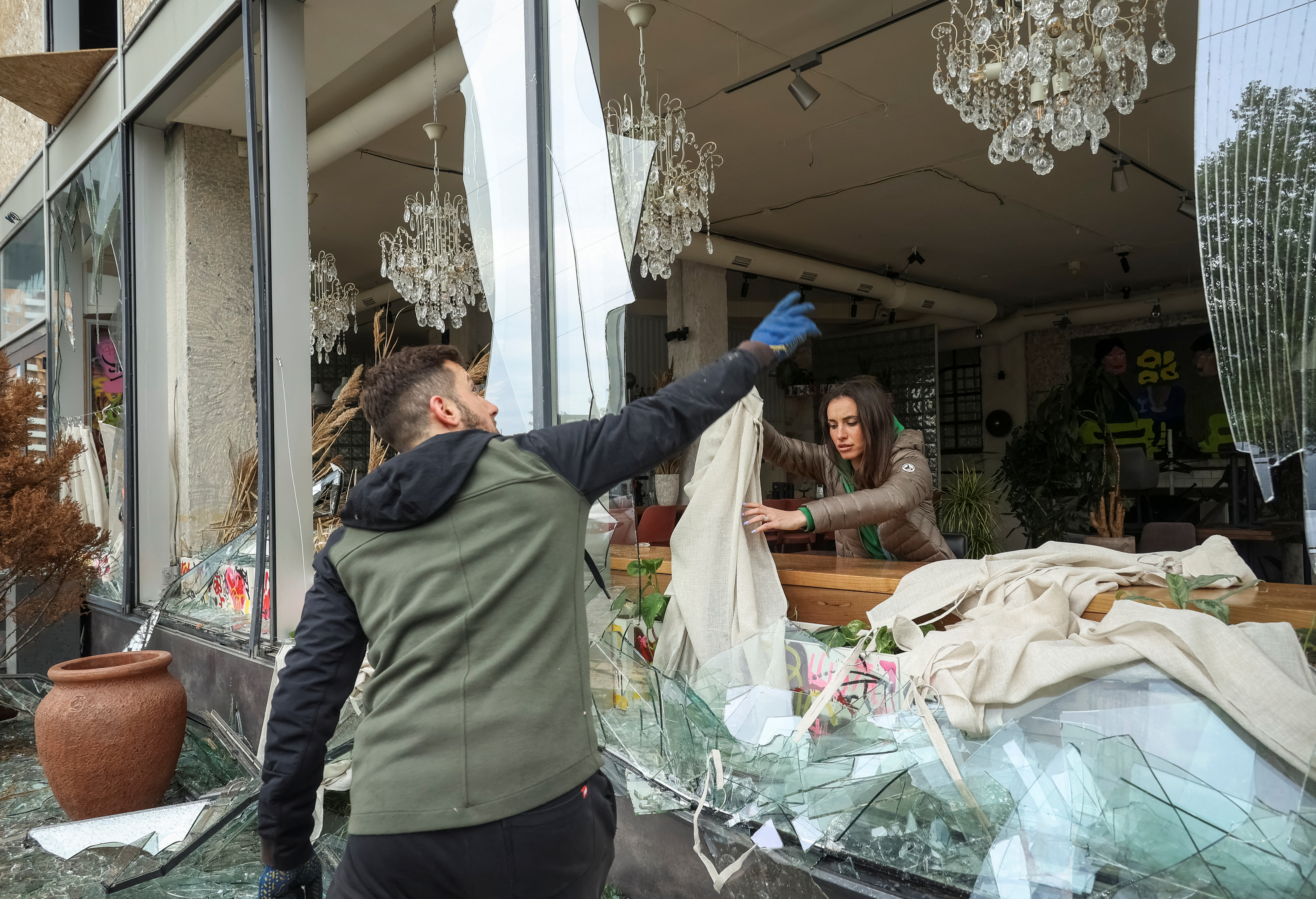 People remove shards of glass from broken windows of a store damaged by a Russian missile strike in Kharkiv, amid Russia's attack on Ukraine April 24, 2024. REUTERS/Sofiia Gatilova