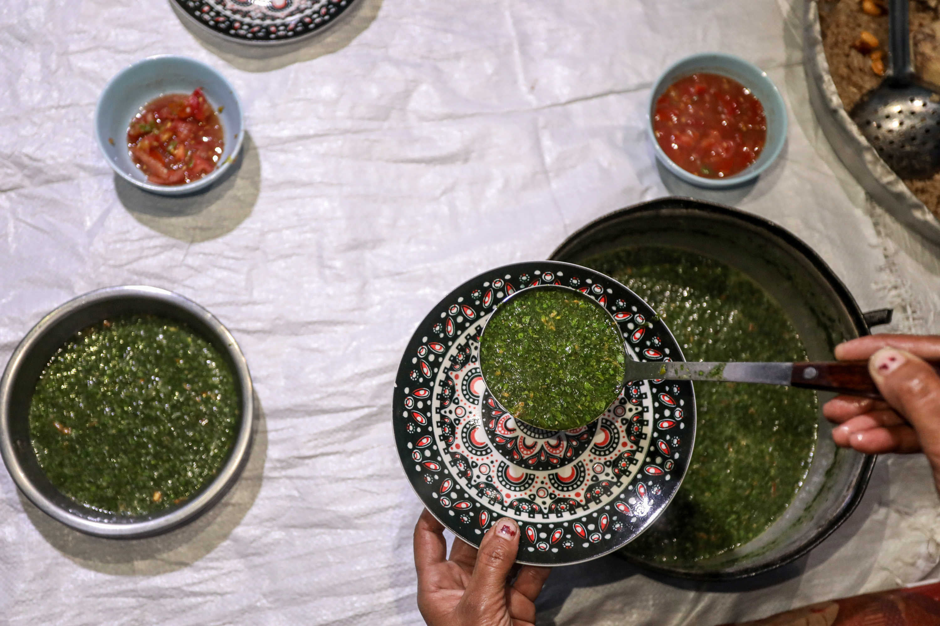 ladle over a bowl serving molokhia