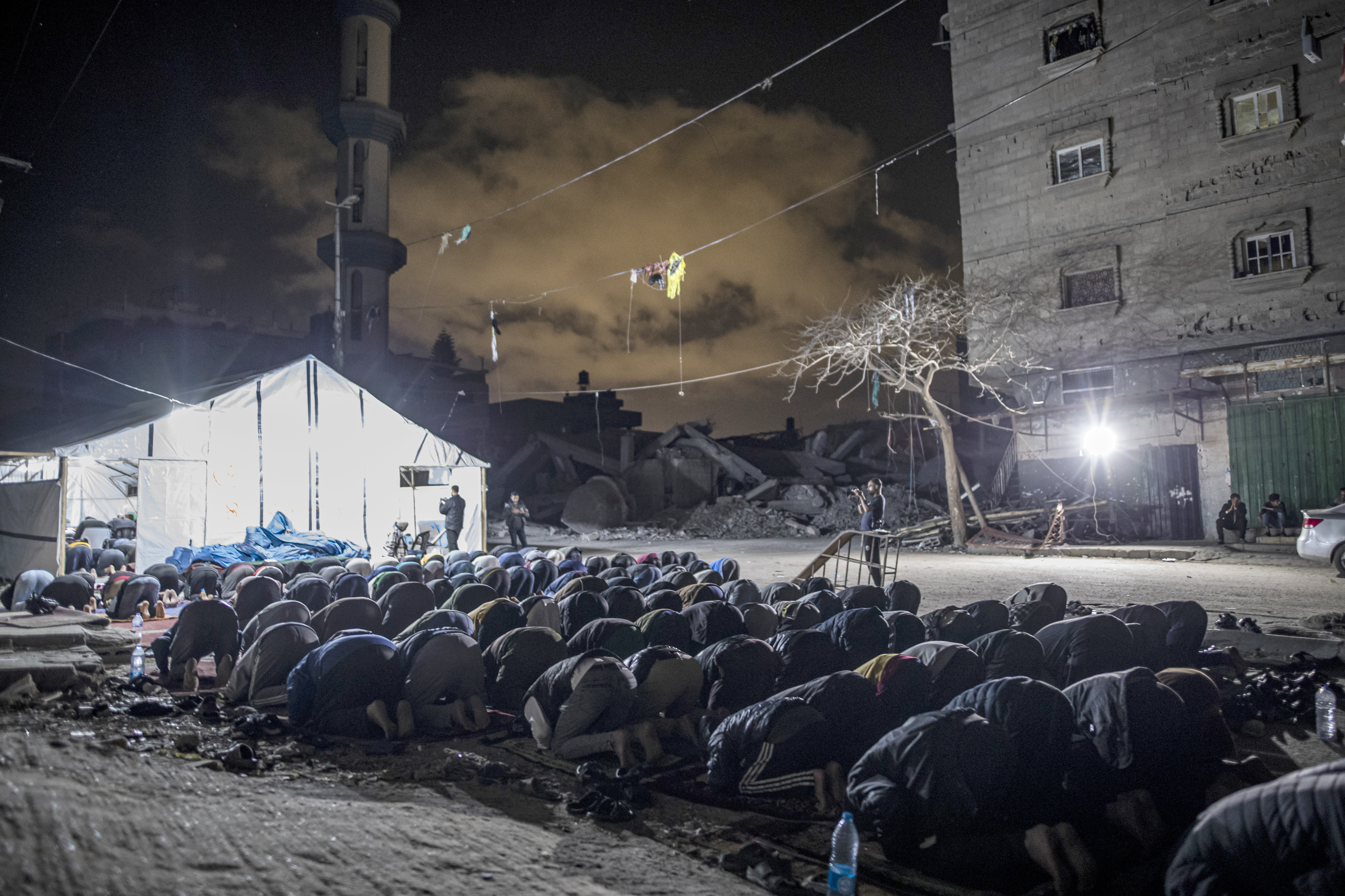 Palestinians gather to perform prayer on the night of Laylat al-Qadr in and outside the tent they have built near the debris of Faruq Mosque in Rafah, Gaza