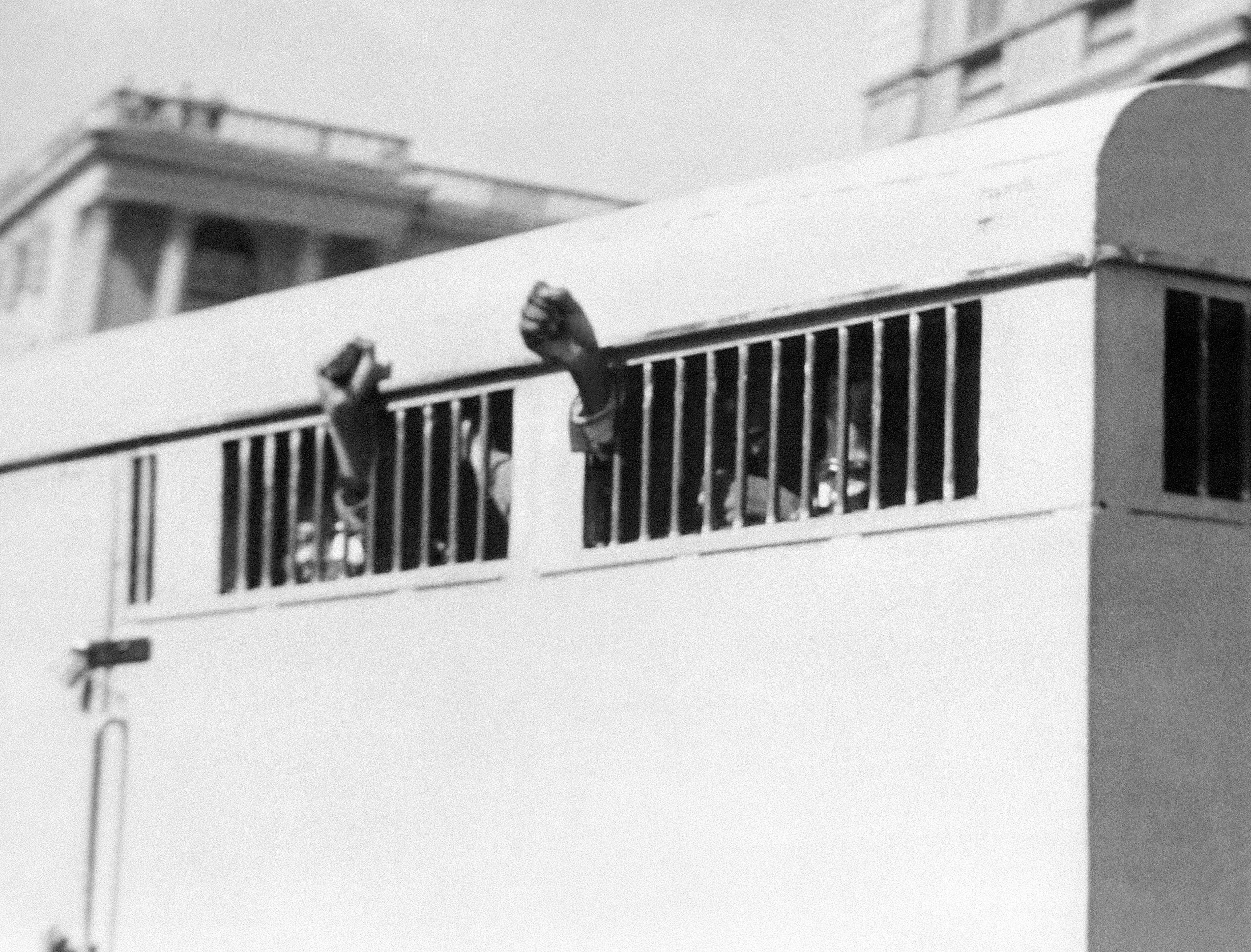Eight men, among them anti-apartheid leader and African National Congress (ANC) member Nelson Mandela, sentenced to life imprisonment in the Rivonia trial leave the Palace of Justice in Pretoria 12 June 1964 with their fists raised in defiance through the barred windows of the prison car. The eight men were accused of conspiracy, sabotage and treason. AFP PHOTO (Photo by AFP)