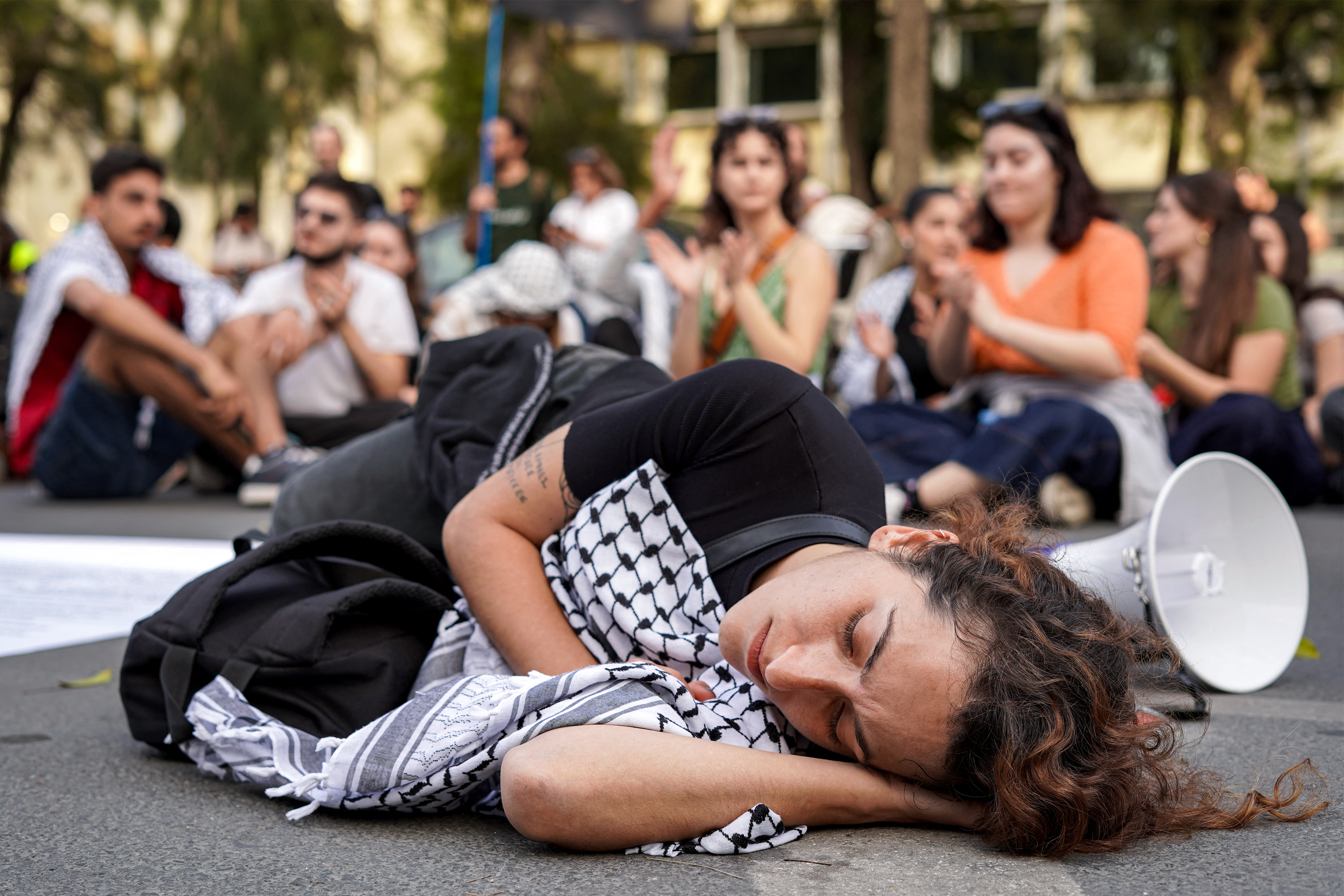 people lie on the ground at a protest with Palestinian flags