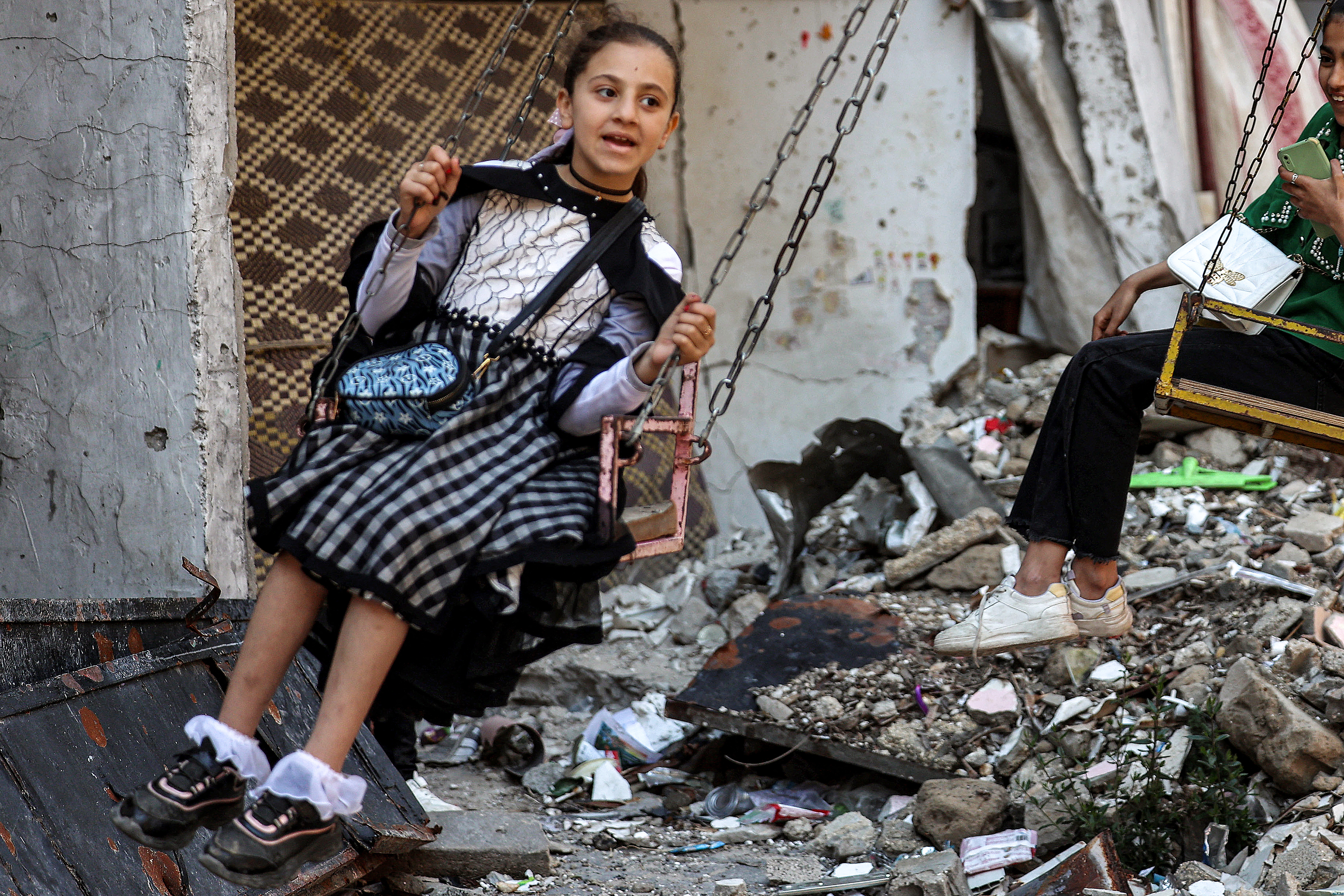 A girl sits in a swing while celebrating on the first day of the Muslim holiday of Eid al-Fitr, after the end of the holy month of Ramadan, in Deir el-Balah in the central Gaza Strip on April 10, 2024, amid the ongoing conflict in the Palestinian territory